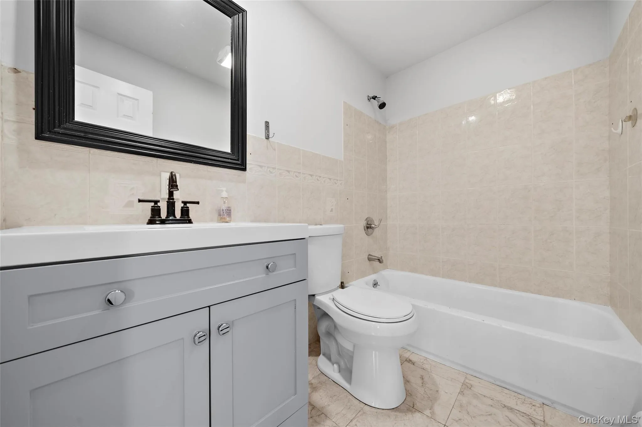 Bathroom with vanity, toilet, tile walls, and shower combination Bathroom with vanity, toilet, tile walls, and shower combination