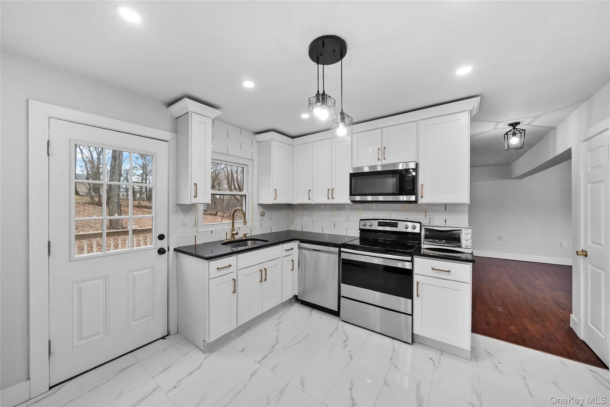 Kitchen with a sink, white cabinets, appliances with stainless steel finishes, dark countertops, and backsplash Kitchen with a sink, white cabinets, appliances with stainless steel finishes, dark countertops, and backsplash