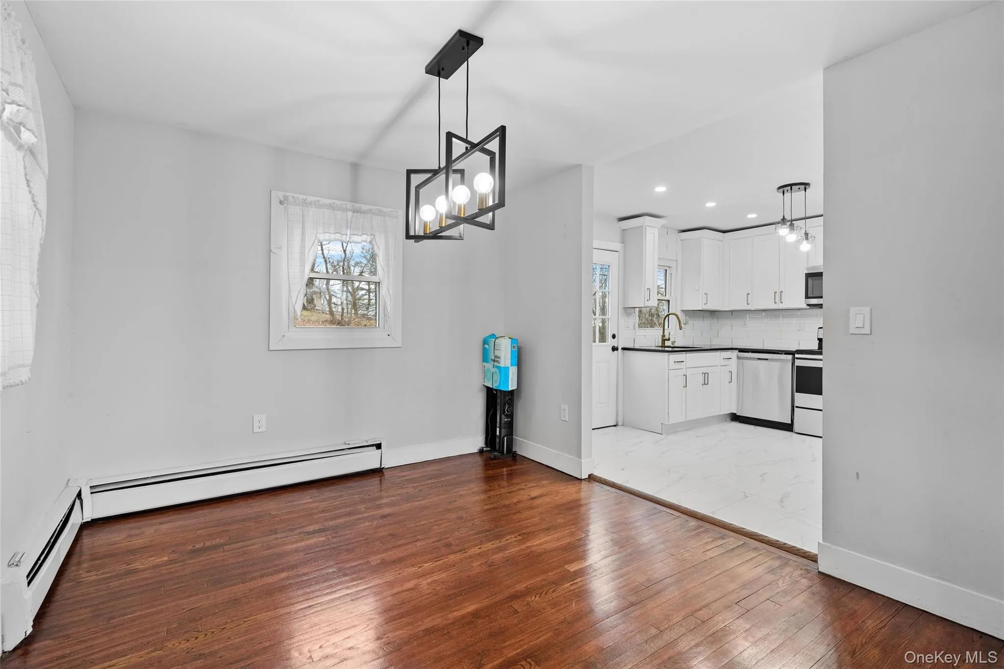 Unfurnished dining area featuring a baseboard heating unit, a notable chandelier, wood-type flooring, and a sink Unfurnished dining area featuring a baseboard heating unit, a notable chandelier, wood-type flooring, and a sink