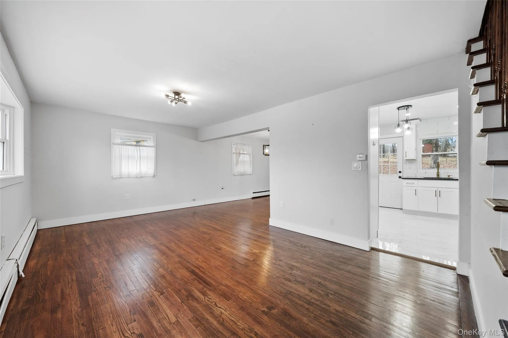 Unfurnished living room featuring a sink, a baseboard heating unit, baseboards, and wood-type flooring Unfurnished living room featuring a sink, a baseboard heating unit, baseboards, and wood-type flooring