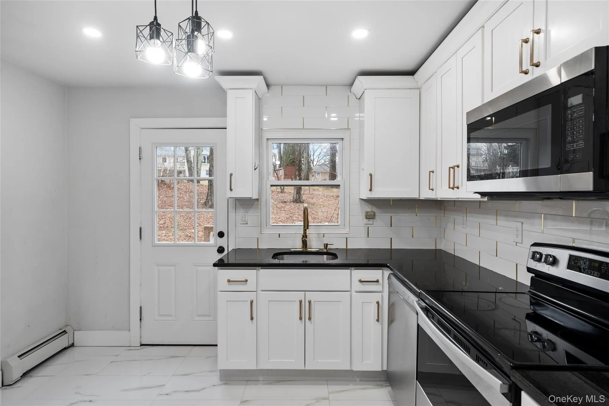 Kitchen with marble finish floor, a sink, dark countertops, stainless steel appliances, and a baseboard radiator Kitchen with marble finish floor, a sink, dark countertops, stainless steel appliances, and a baseboard radiator