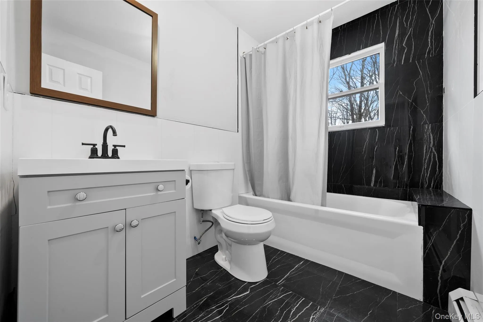 Bathroom with toilet, marble finish floor, shower / tub combo, baseboard heating, and vanity Bathroom with toilet, marble finish floor, shower / tub combo, baseboard heating, and vanity