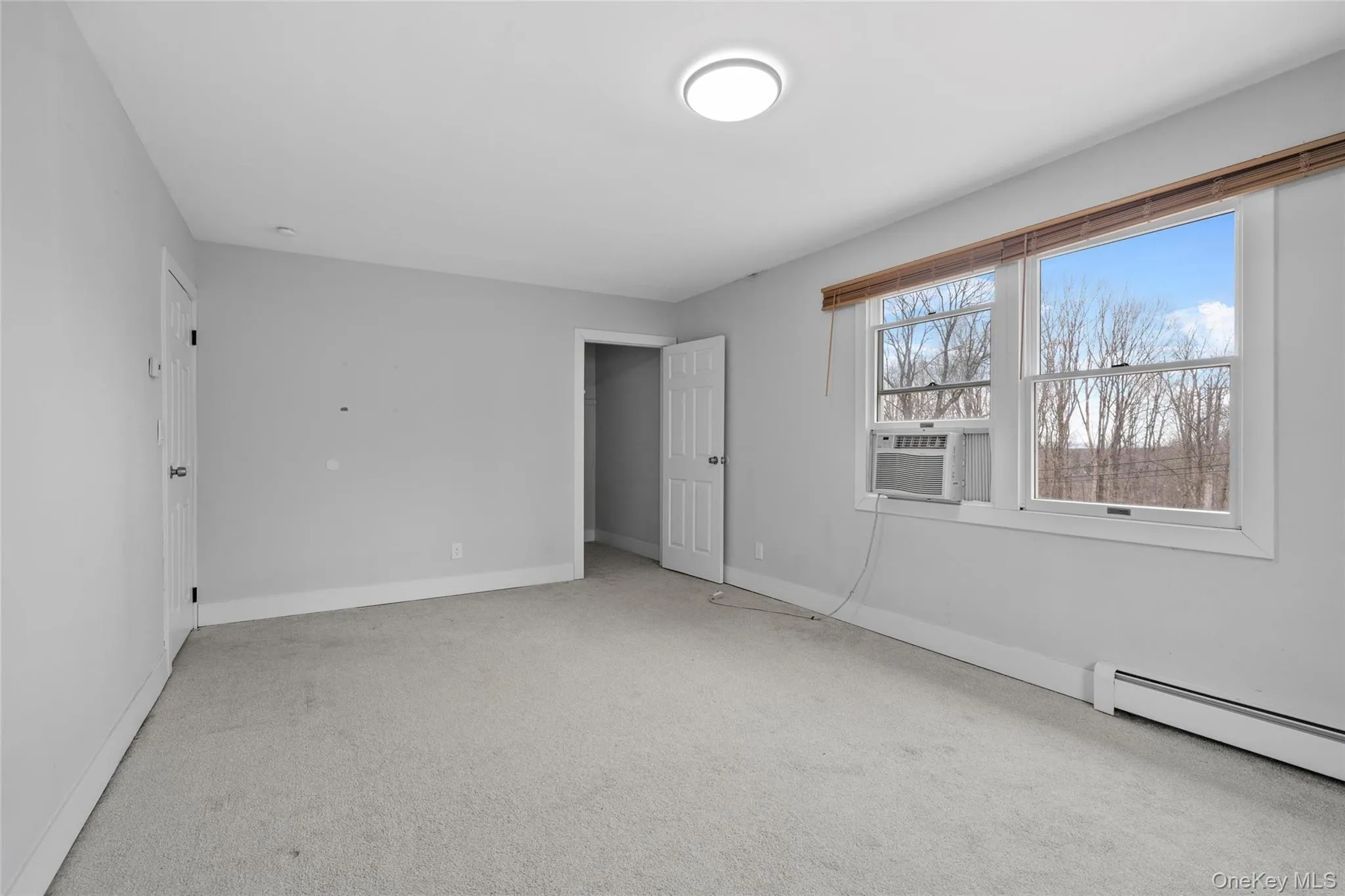 Unfurnished bedroom with cooling unit, baseboards, baseboard heating, and carpet floors Unfurnished bedroom with cooling unit, baseboards, baseboard heating, and carpet floors