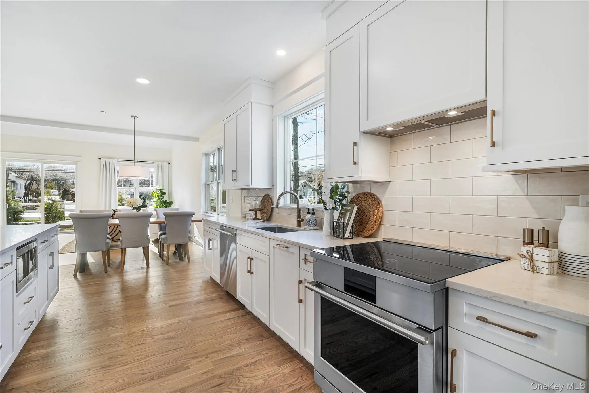 Kitchen with sink, white cabinetry, hanging light fixtures, stainless steel appliances, and light wood-type flooring Kitchen with sink, white cabinetry, hanging light fixtures, stainless steel appliances, and light wood-type flooring