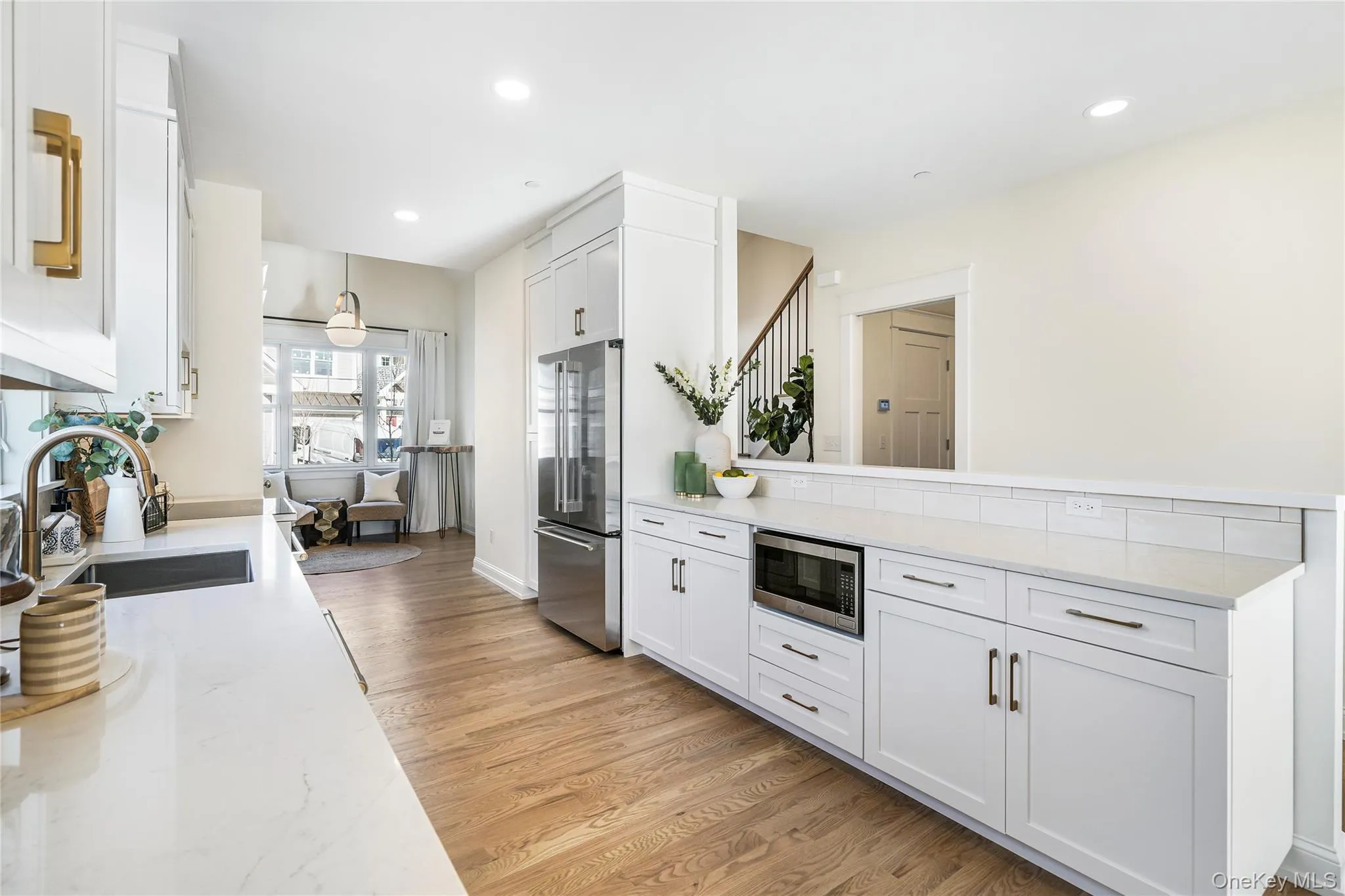 Kitchen with sink, white cabinetry, stainless steel appliances, light stone countertops, and light wood-type flooring Kitchen with sink, white cabinetry, stainless steel appliances, light stone countertops, and light wood-type flooring