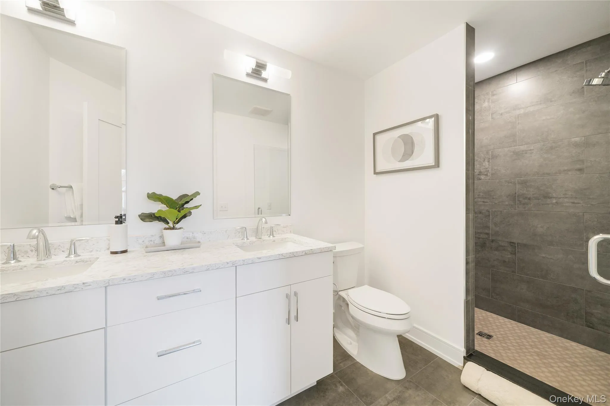 Bathroom with a tile shower, vanity, tile patterned floors, and toilet Bathroom with a tile shower, vanity, tile patterned floors, and toilet