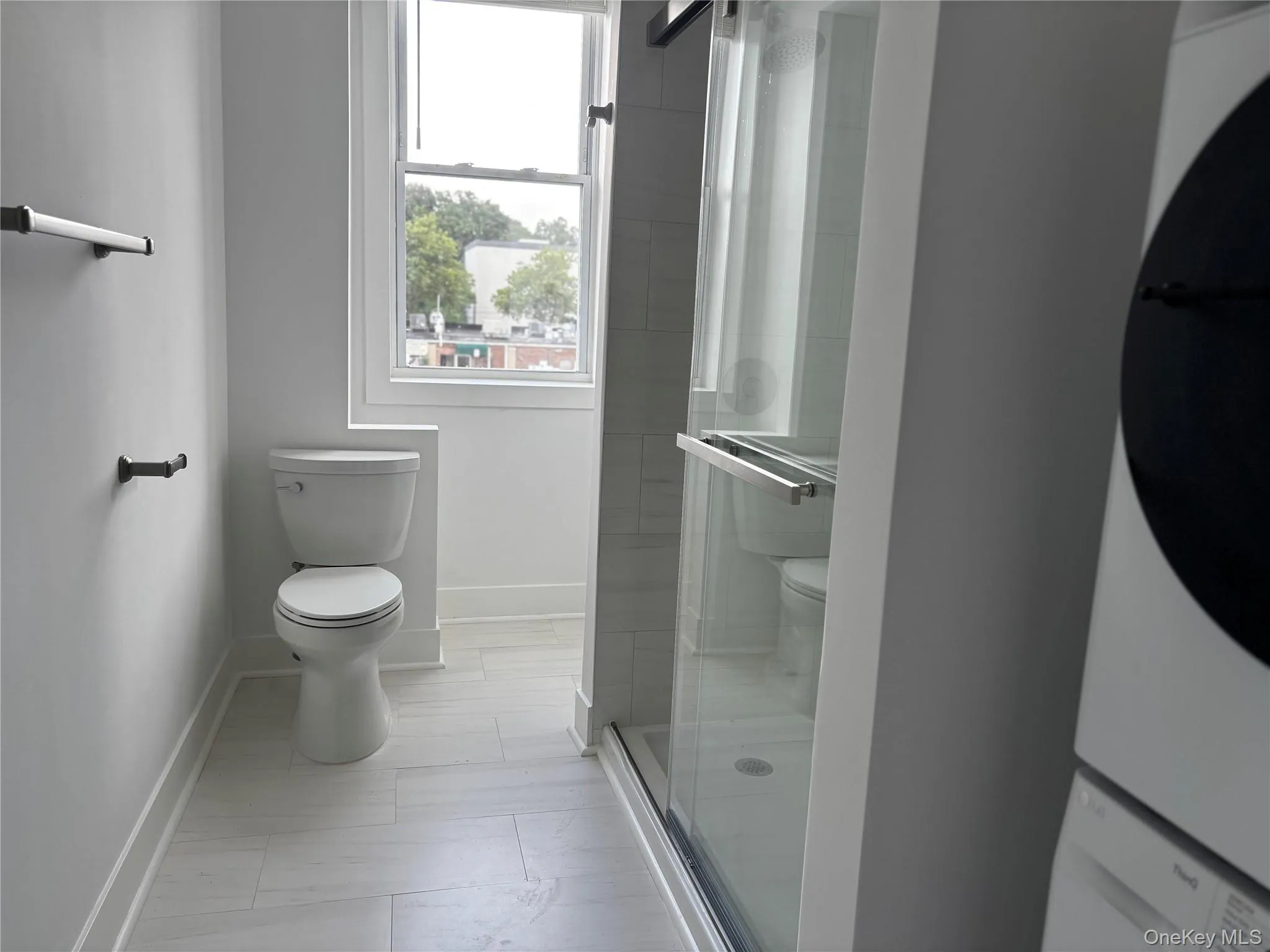 Full bathroom with estacked washer and dryer and a shower stall Full bathroom with estacked washer and dryer and a shower stall