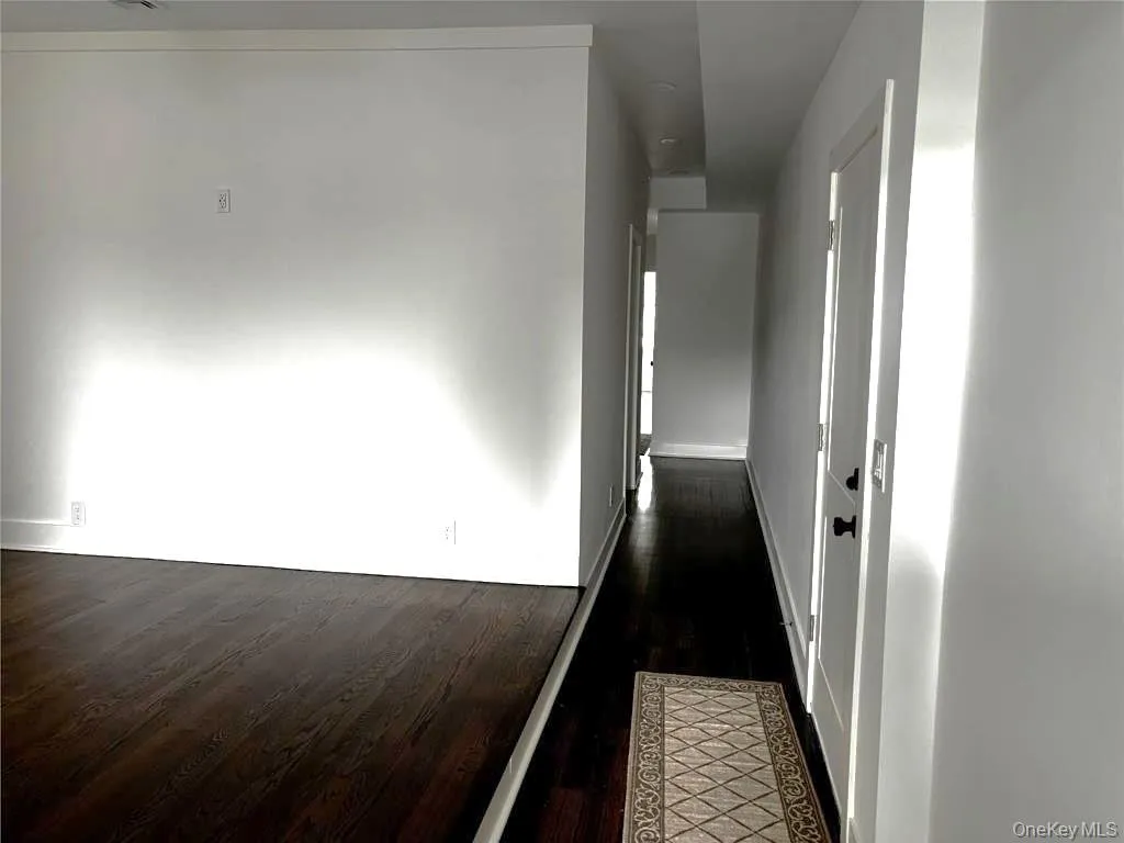 Corridor featuring dark wood-style flooring and baseboards Corridor featuring dark wood-style flooring and baseboards