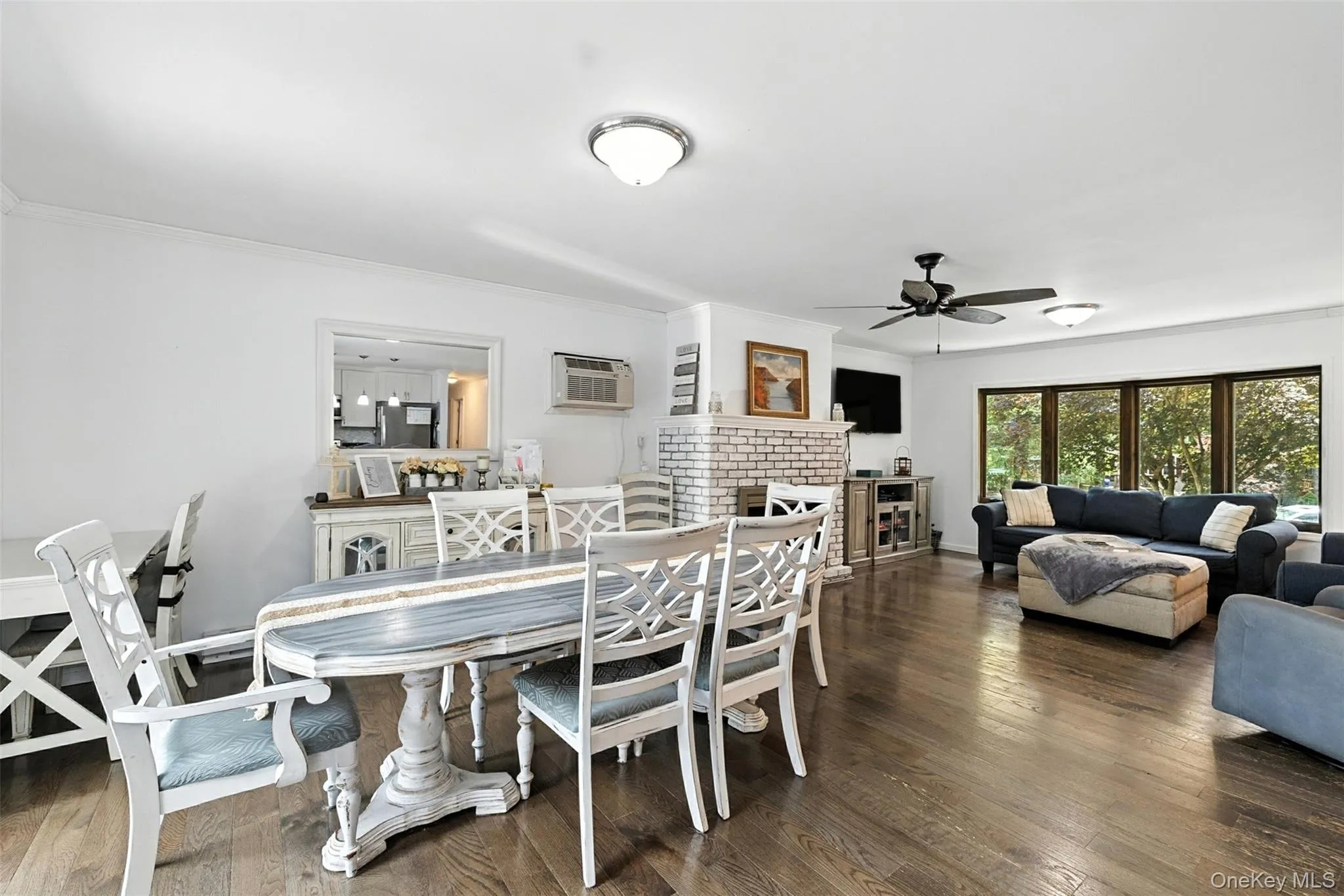 Dining area featuring ceiling fan, a fireplace, wood finished floors, ornamental molding, and a wall mounted air conditioner Dining area featuring ceiling fan, a fireplace, wood finished floors, ornamental molding, and a wall mounted air conditioner