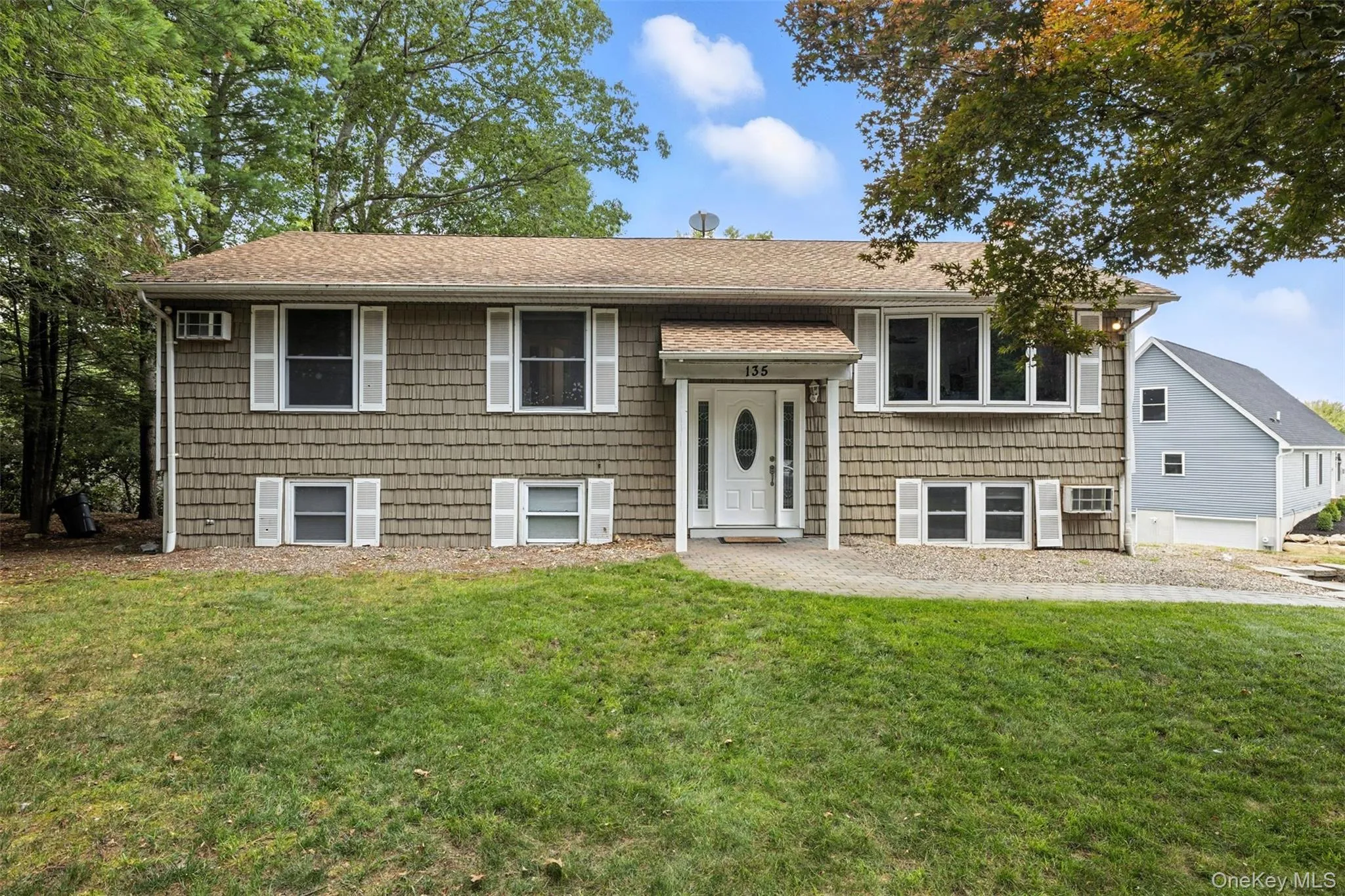 Bi-level home with a front lawn and roof with shingles Bi-level home with a front lawn and roof with shingles