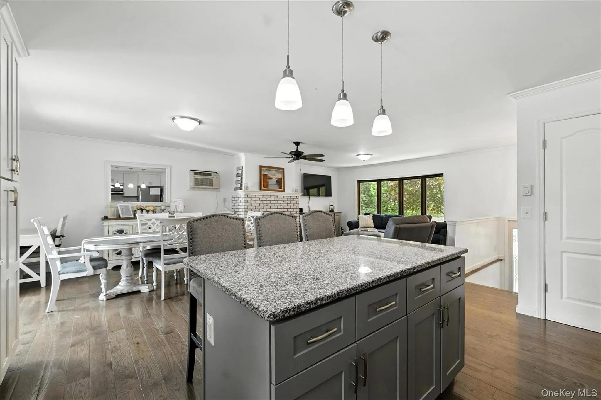 Kitchen featuring a center island, a ceiling fan, dark wood-type flooring, light stone counters, and decorative light fixtures Kitchen featuring a center island, a ceiling fan, dark wood-type flooring, light stone counters, and decorative light fixtures