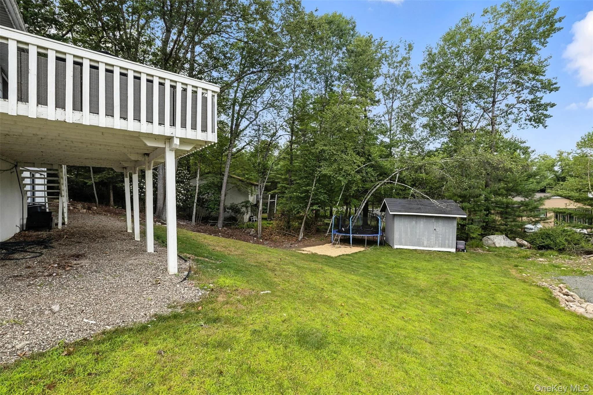 View of green lawn featuring a storage unit, a trampoline, stairway, and a wooden deck View of green lawn featuring a storage unit, a trampoline, stairway, and a wooden deck