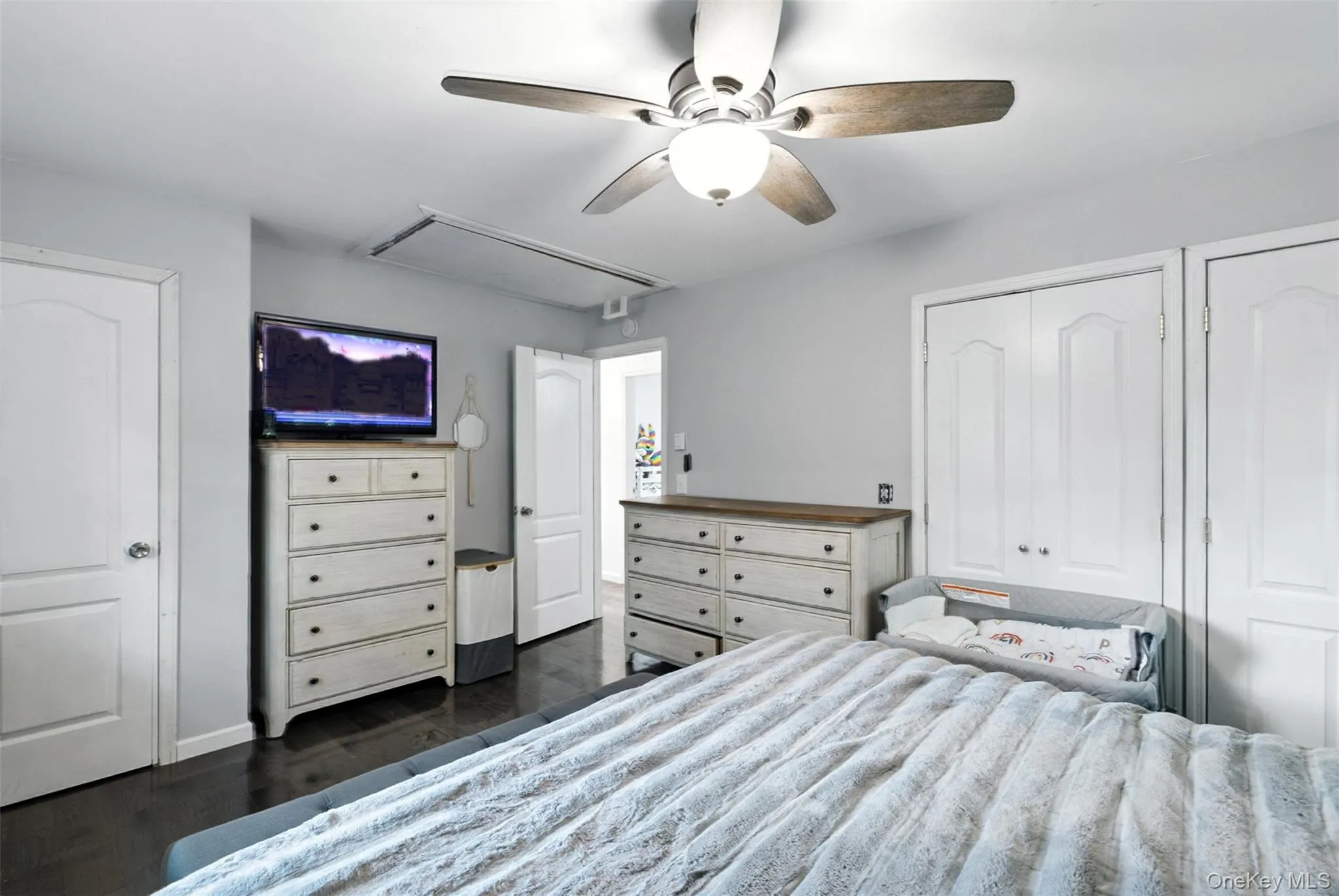 Bedroom with attic access, dark wood-type flooring, ceiling fan, and multiple closets Bedroom with attic access, dark wood-type flooring, ceiling fan, and multiple closets