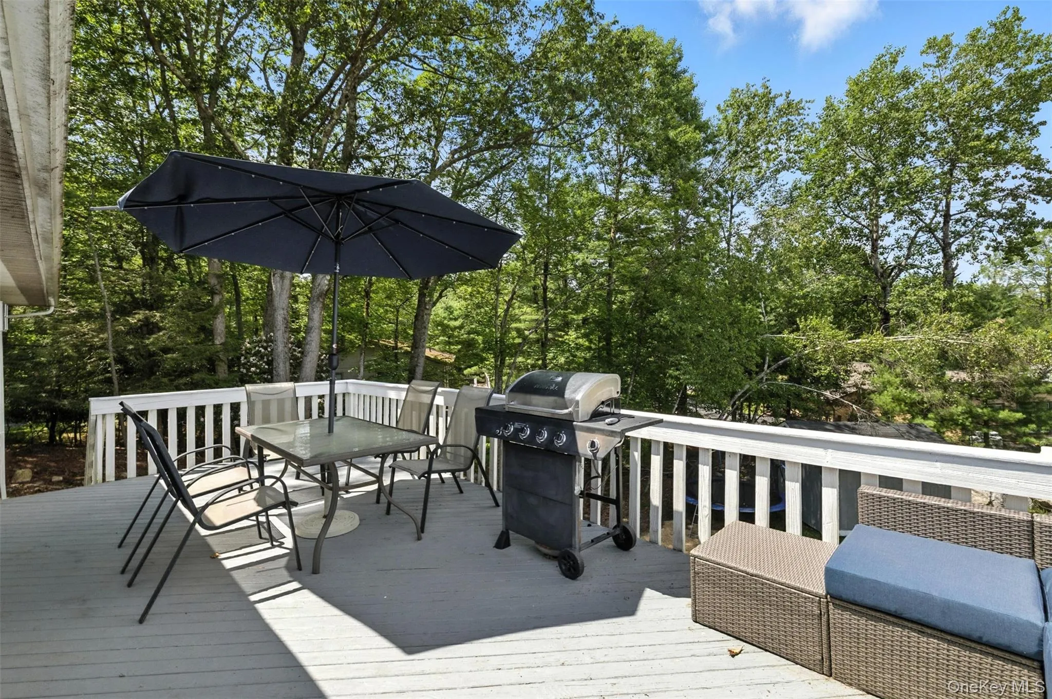 Deck featuring outdoor dining area, a grill, and view of scattered trees Deck featuring outdoor dining area, a grill, and view of scattered trees