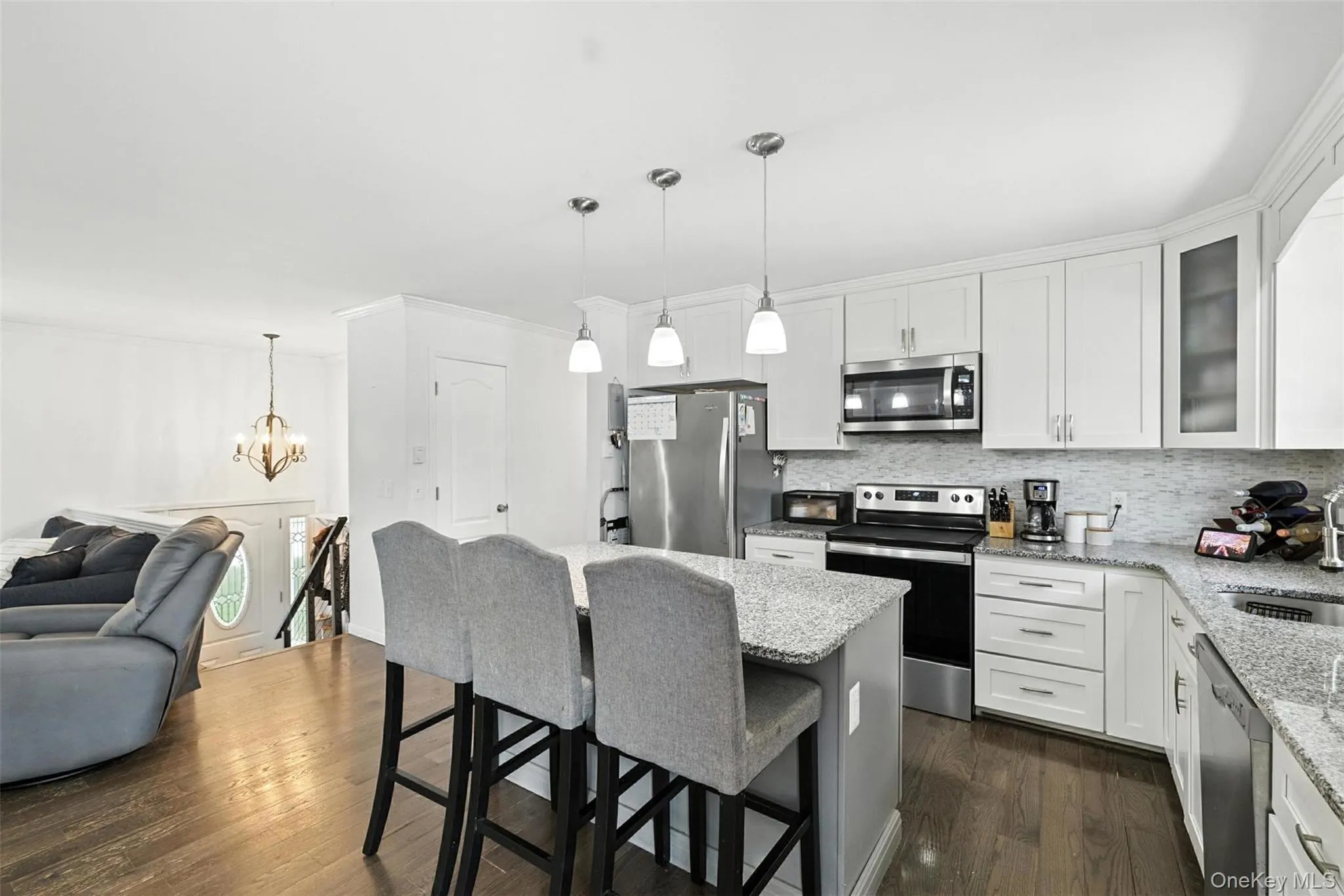 Kitchen with appliances with stainless steel finishes, decorative backsplash, open floor plan, a kitchen breakfast bar, and light stone countertops Kitchen with appliances with stainless steel finishes, decorative backsplash, open floor plan, a kitchen breakfast bar, and light stone countertops
