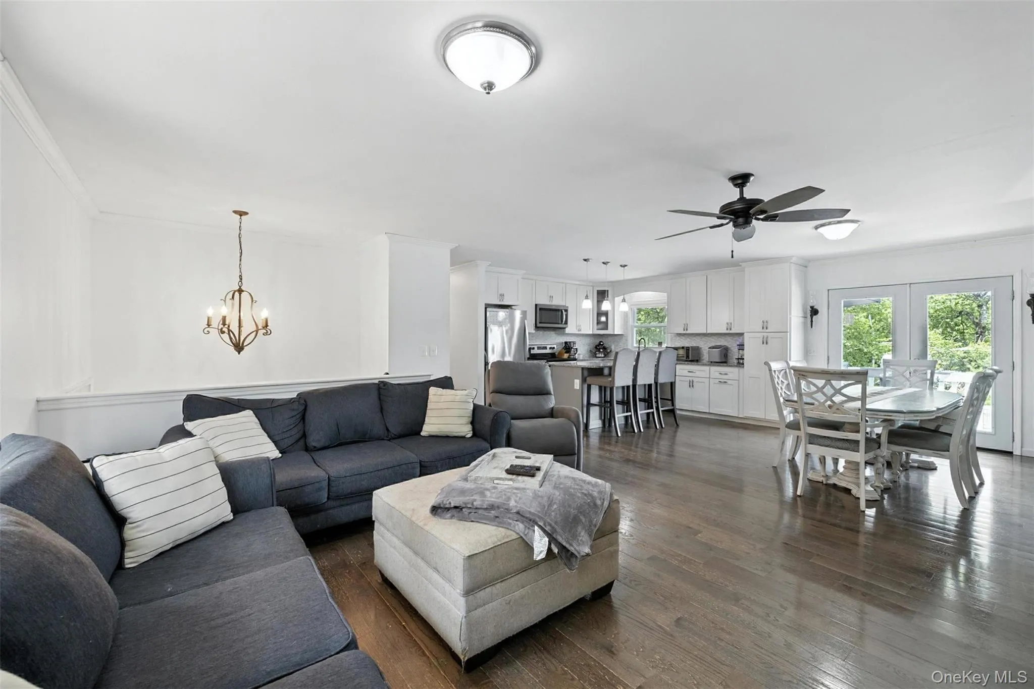 Living room with a chandelier, ornamental molding, ceiling fan, and dark wood-type flooring Living room with a chandelier, ornamental molding, ceiling fan, and dark wood-type flooring