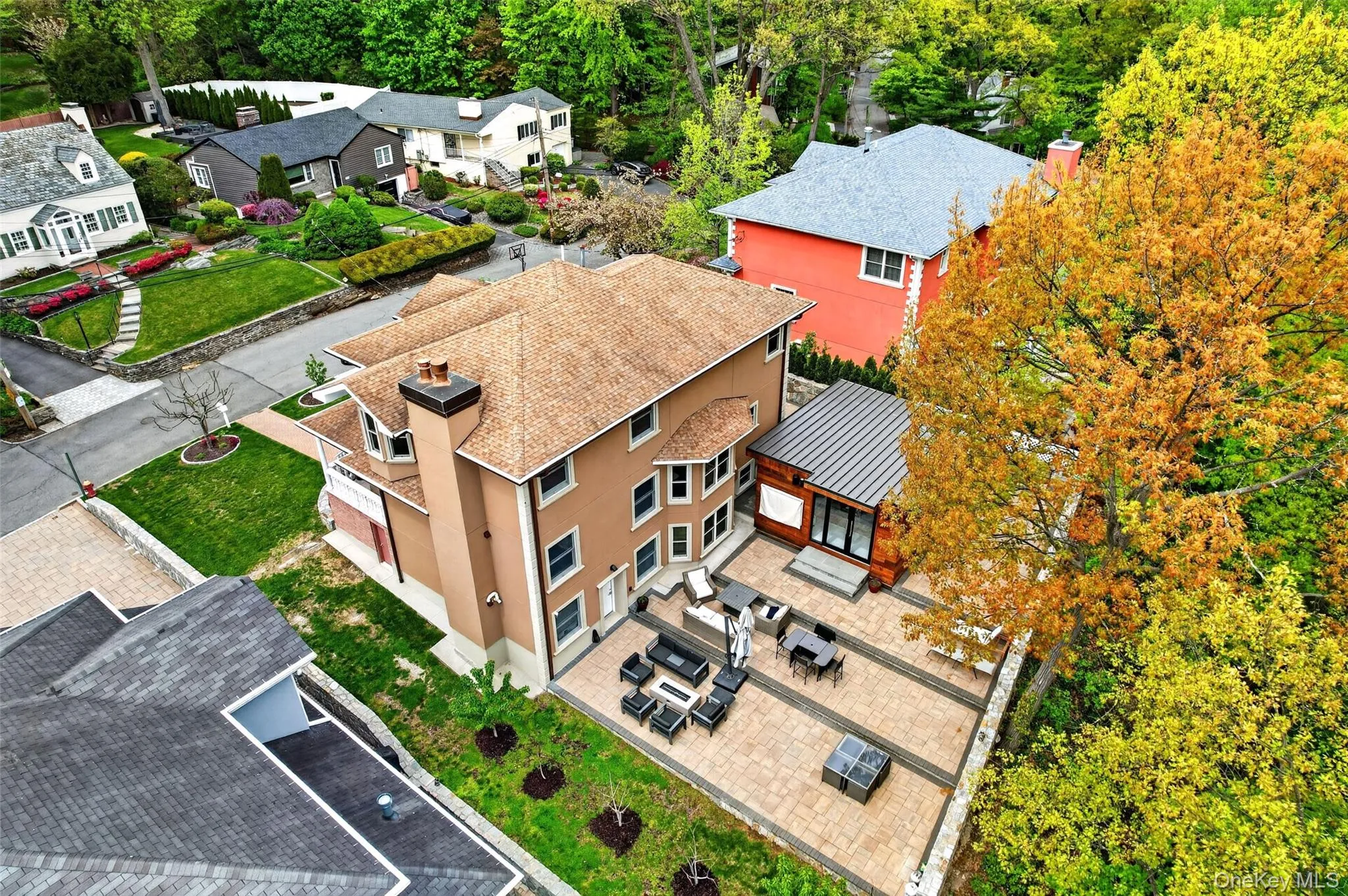 Spacious paved patio area featuring a modern detached structure with large windows and a metal roof Spacious paved patio area featuring a modern detached structure with large windows and a metal roof