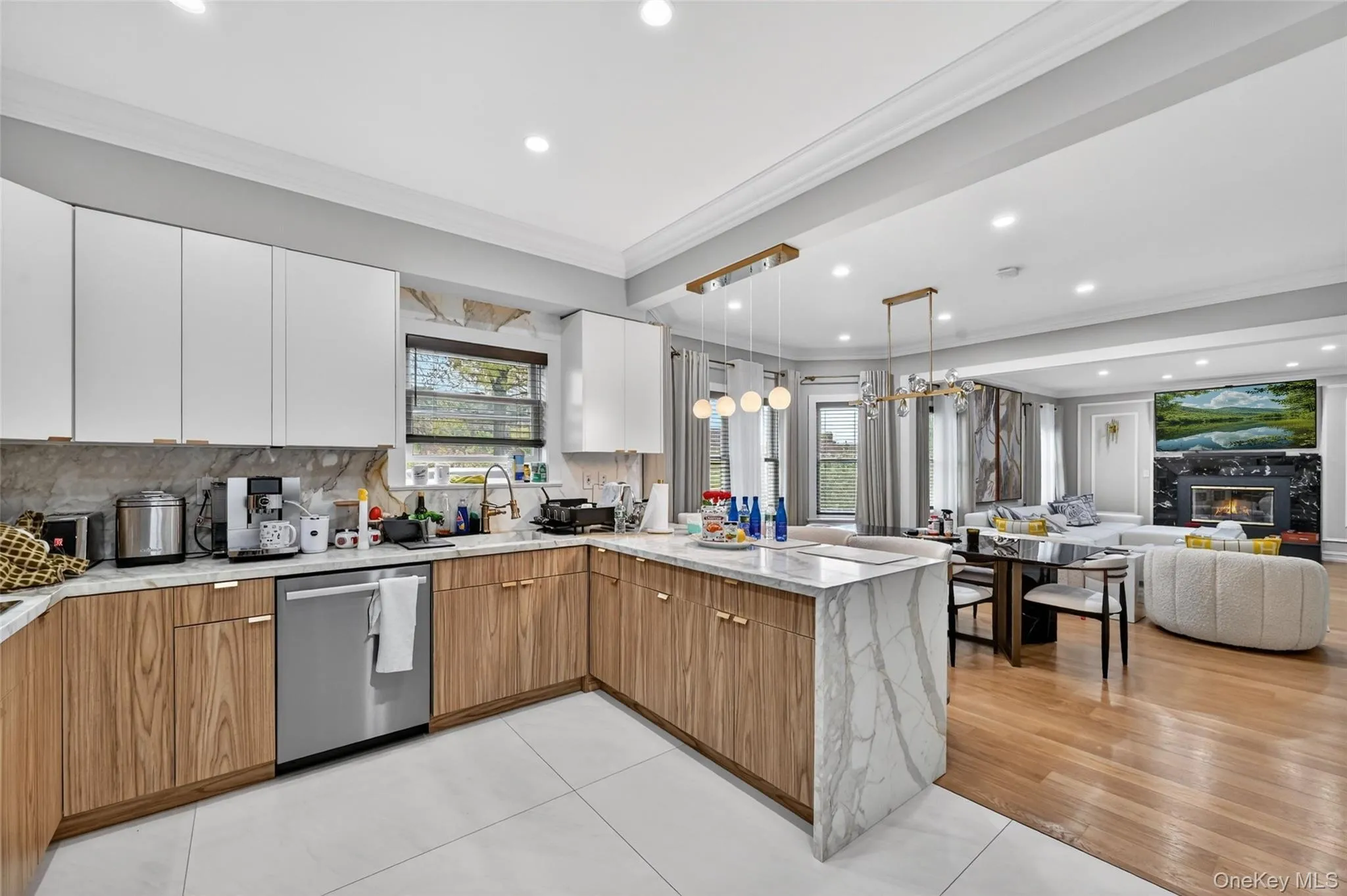 Contemporary kitchen featuring white upper cabinetry, wood-finish lower cabinetry, and stone countertops extending to a waterfall island Contemporary kitchen featuring white upper cabinetry, wood-finish lower cabinetry, and stone countertops extending to a waterfall island