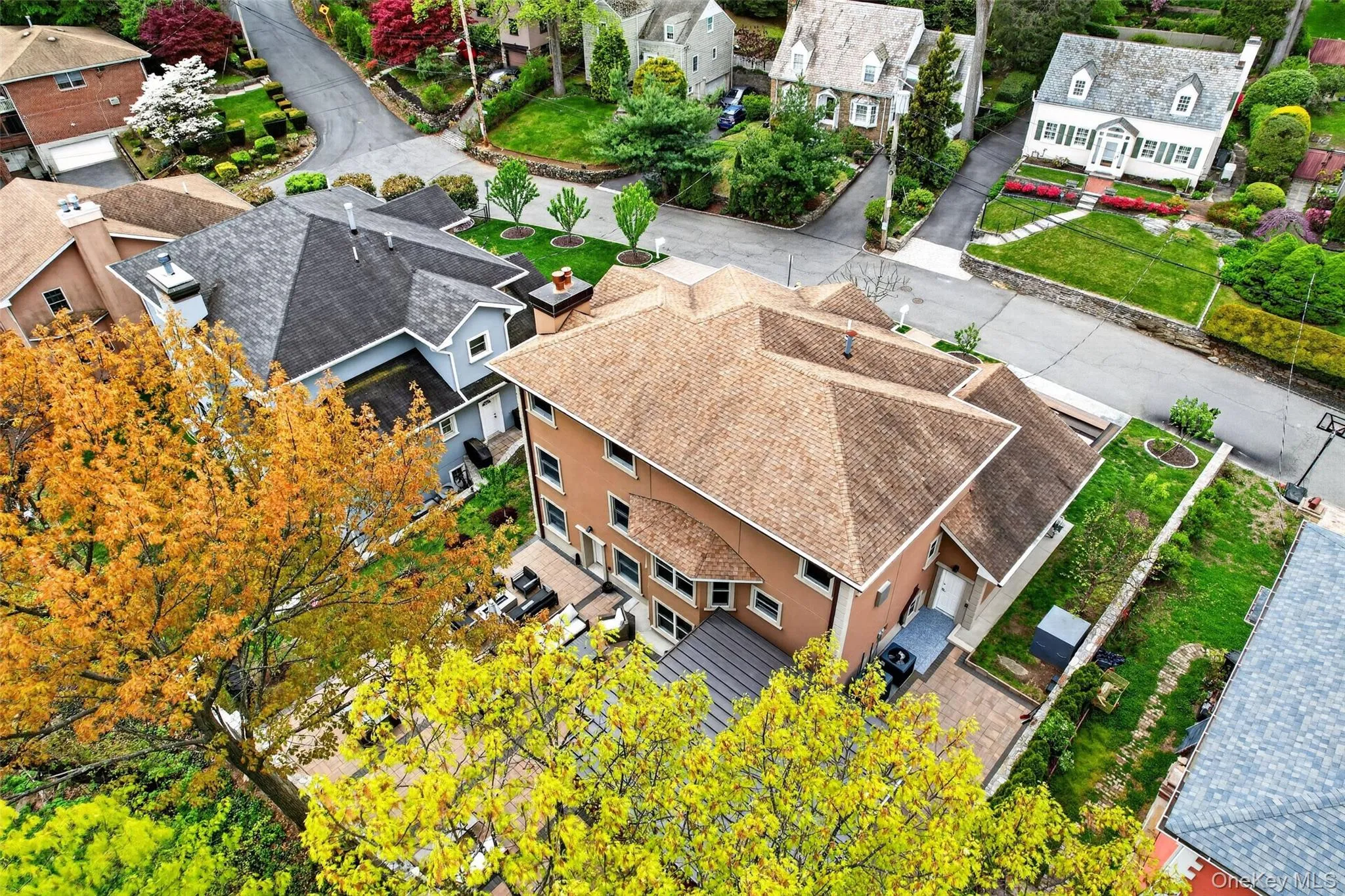 Aerial perspective showcasing a multi-level dwelling with a light brown shingle roof, tan stucco exterior, and multiple windows Aerial perspective showcasing a multi-level dwelling with a light brown shingle roof, tan stucco exterior, and multiple windows