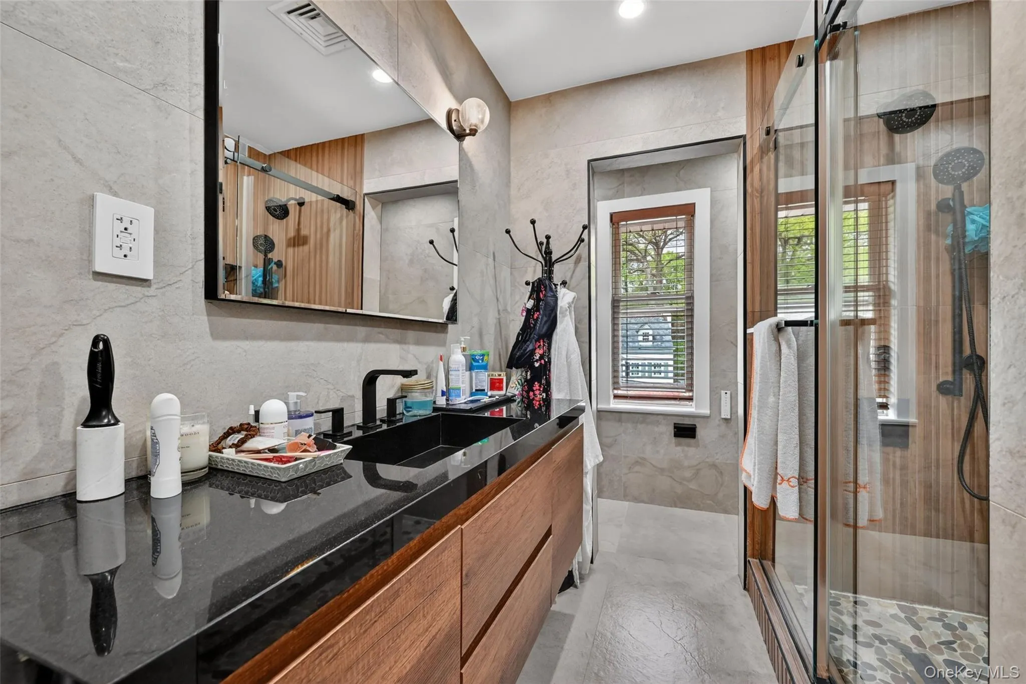 Bathroom featuring a floating wood-finish vanity with a black countertop and integrated sink Bathroom featuring a floating wood-finish vanity with a black countertop and integrated sink