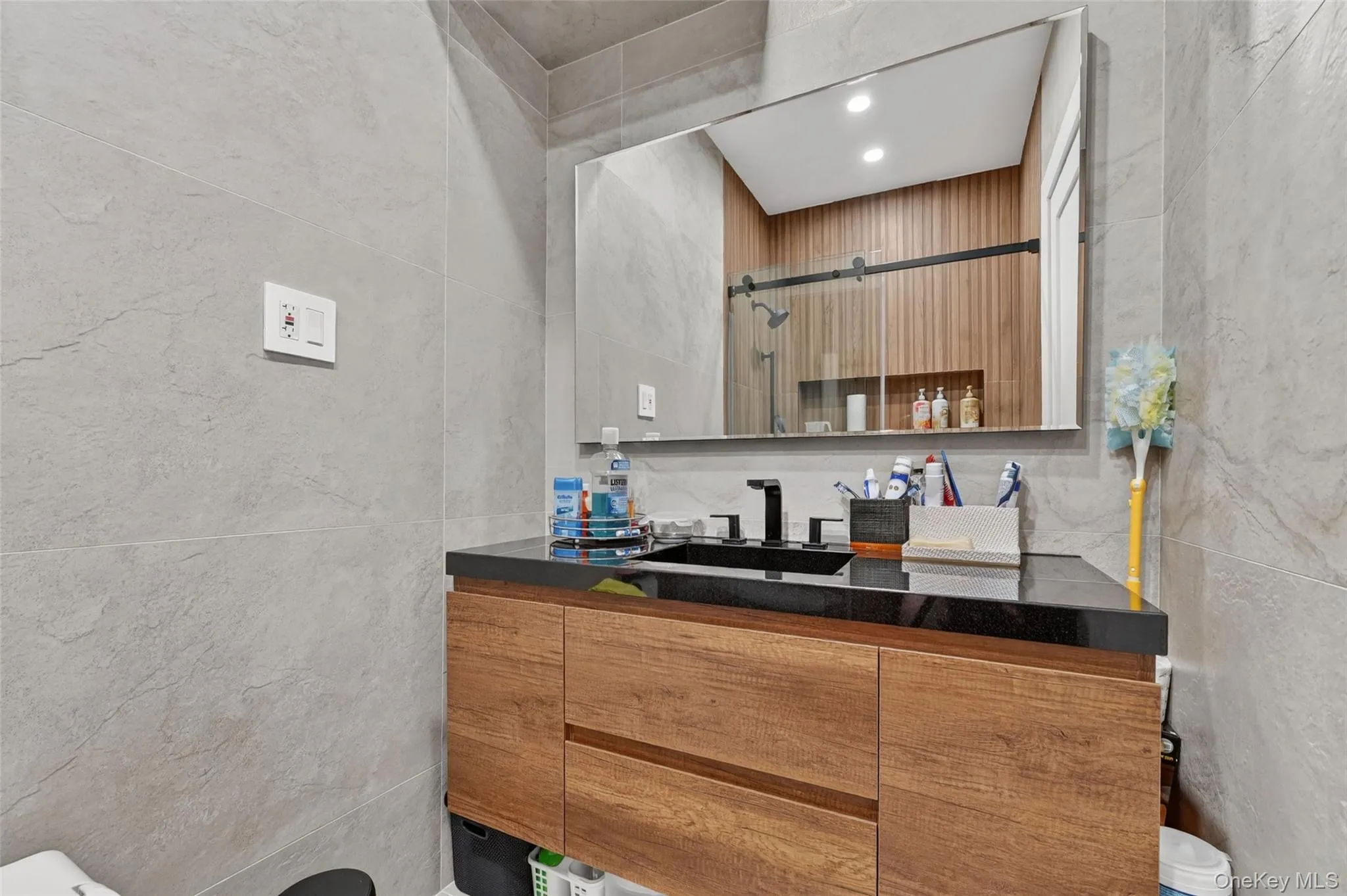 Modern bathroom vanity with wood-finish cabinetry, black countertop, and undermount sink Modern bathroom vanity with wood-finish cabinetry, black countertop, and undermount sink