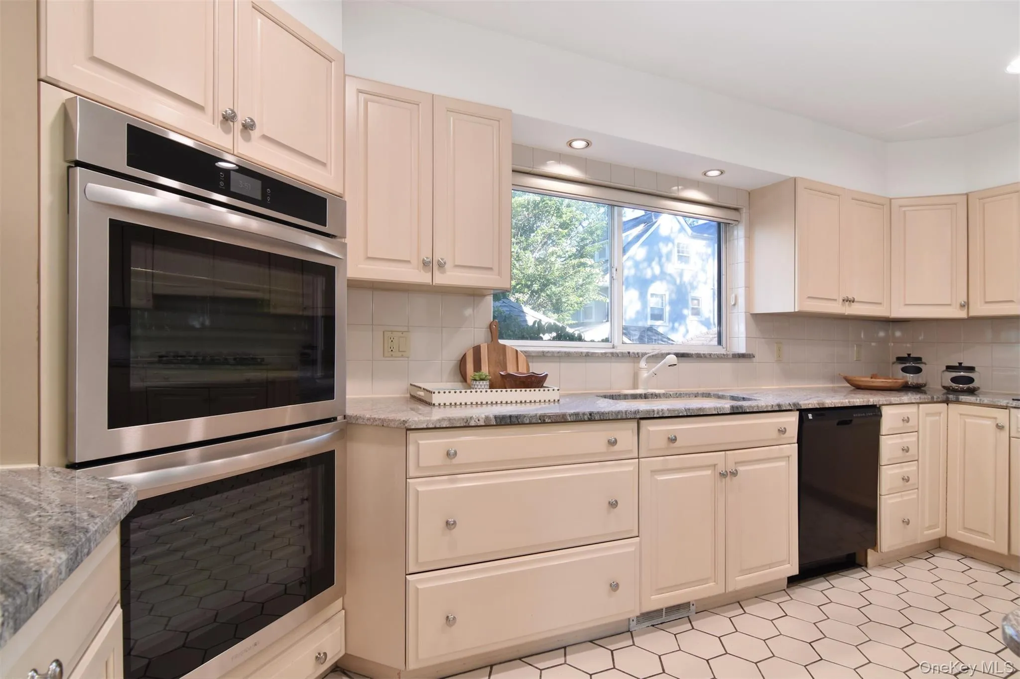 Kitchen featuring stainless steel double oven, cream cabinets, black dishwasher, tasteful backsplash, and recessed lighting Kitchen featuring stainless steel double oven, cream cabinets, black dishwasher, tasteful backsplash, and recessed lighting