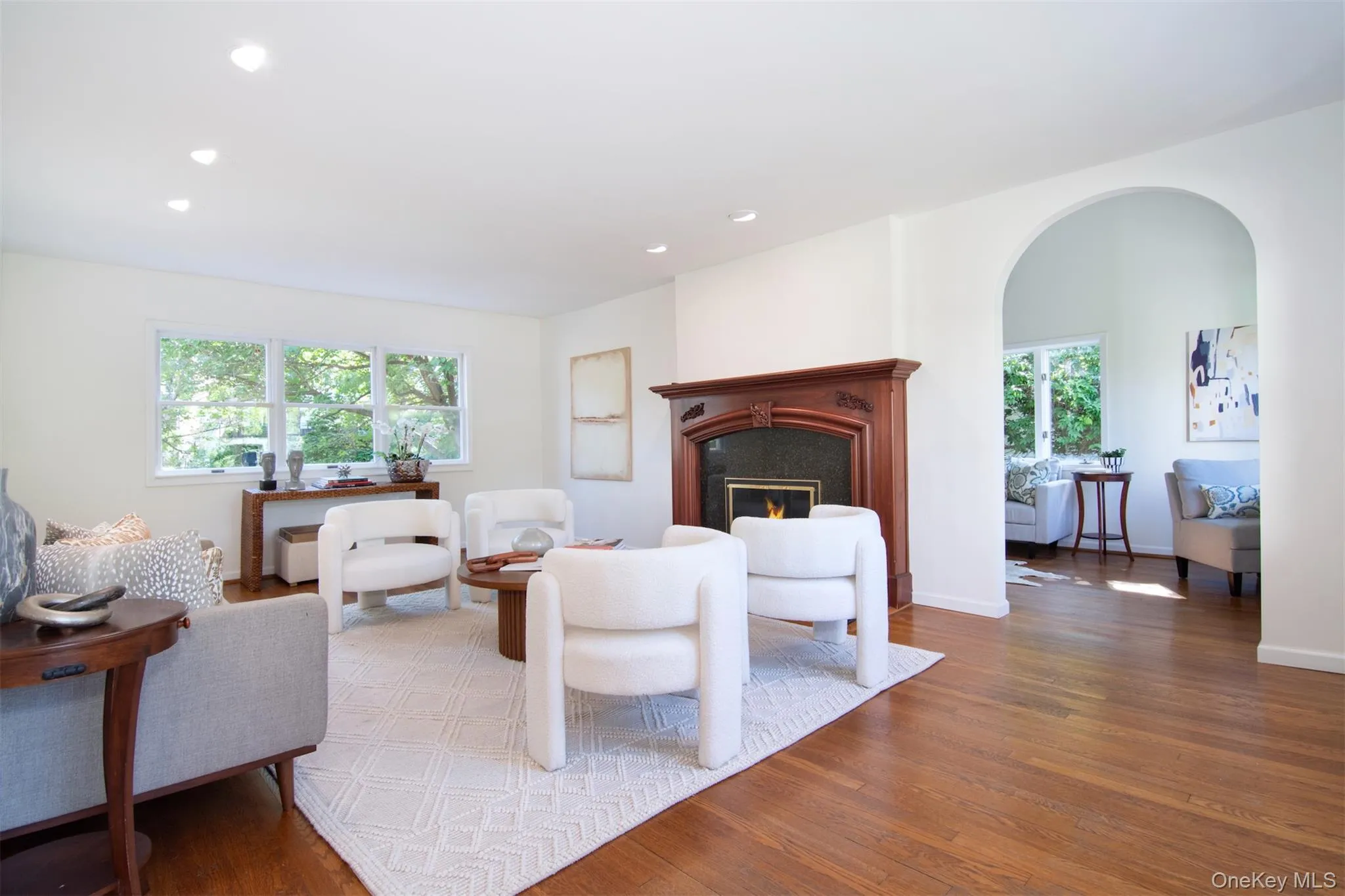 Living room with wood finished floors, recessed lighting, a fireplace, and arched walkways Living room with wood finished floors, recessed lighting, a fireplace, and arched walkways