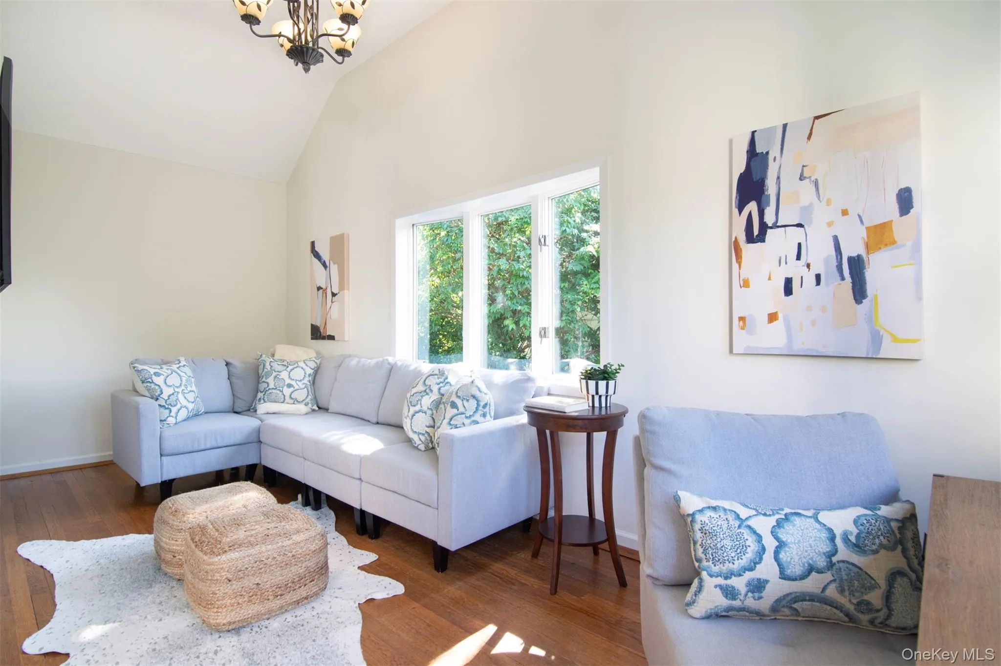 Living room featuring wood finished floors, a chandelier, and high vaulted ceiling Living room featuring wood finished floors, a chandelier, and high vaulted ceiling