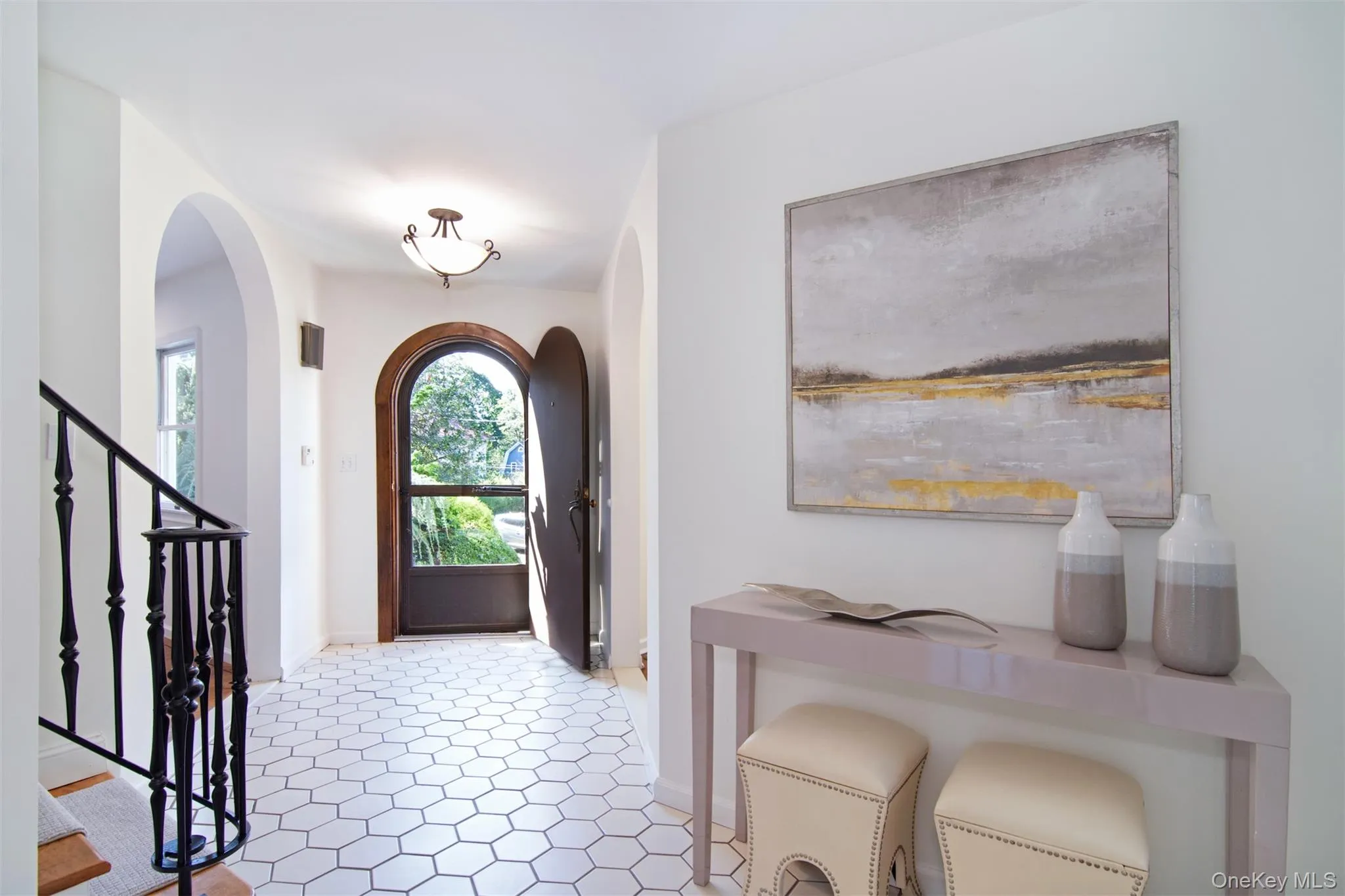 Foyer entrance featuring stairs, arched walkways, and light tile patterned floors Foyer entrance featuring stairs, arched walkways, and light tile patterned floors