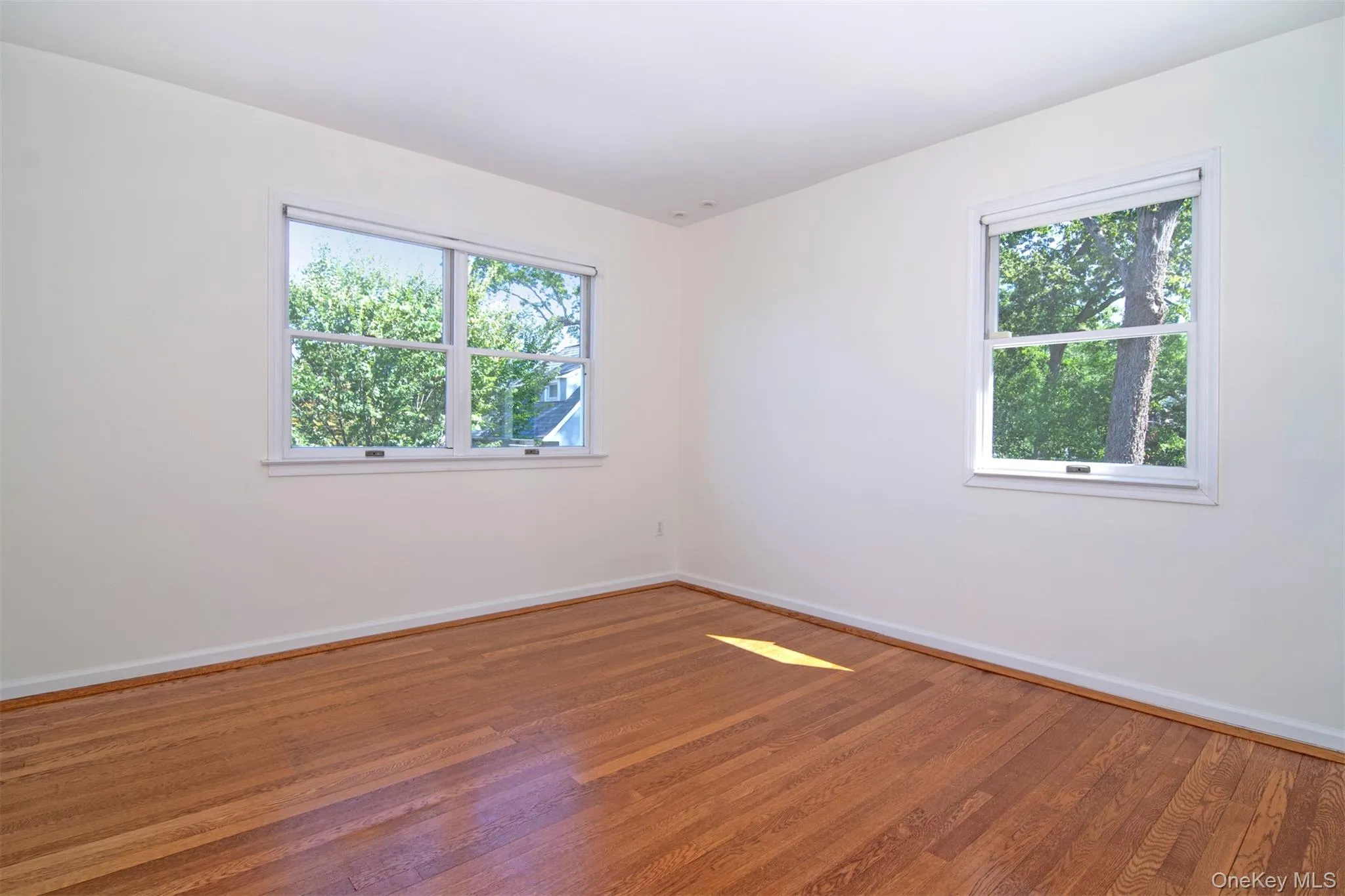 Empty room featuring wood finished floors and baseboards Empty room featuring wood finished floors and baseboards
