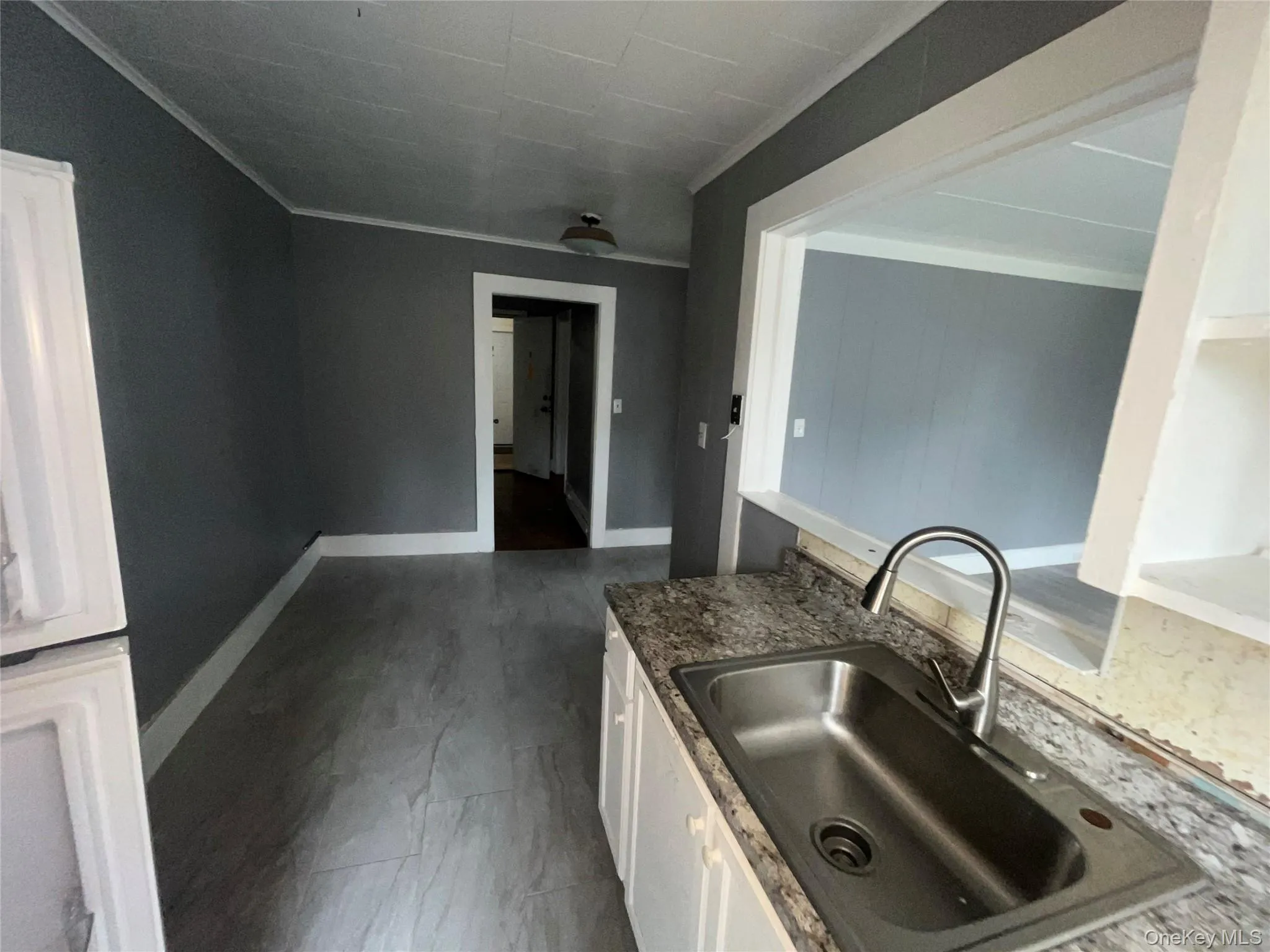 Kitchen featuring white cabinetry, crown molding, and dark stone countertops Kitchen featuring white cabinetry, crown molding, and dark stone countertops