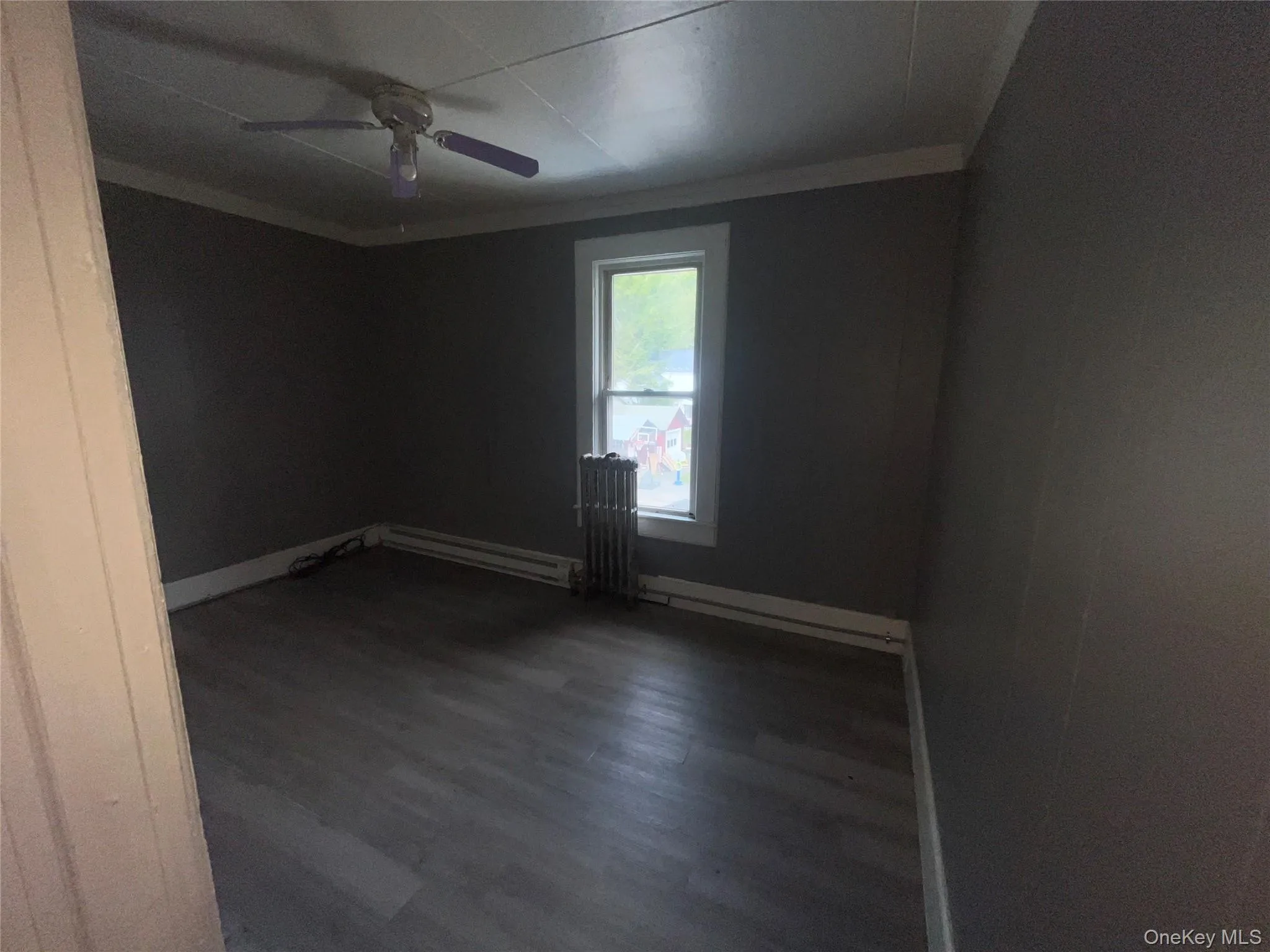 Unfurnished room featuring wood finished floors, crown molding, baseboard heating, and radiator Unfurnished room featuring wood finished floors, crown molding, baseboard heating, and radiator