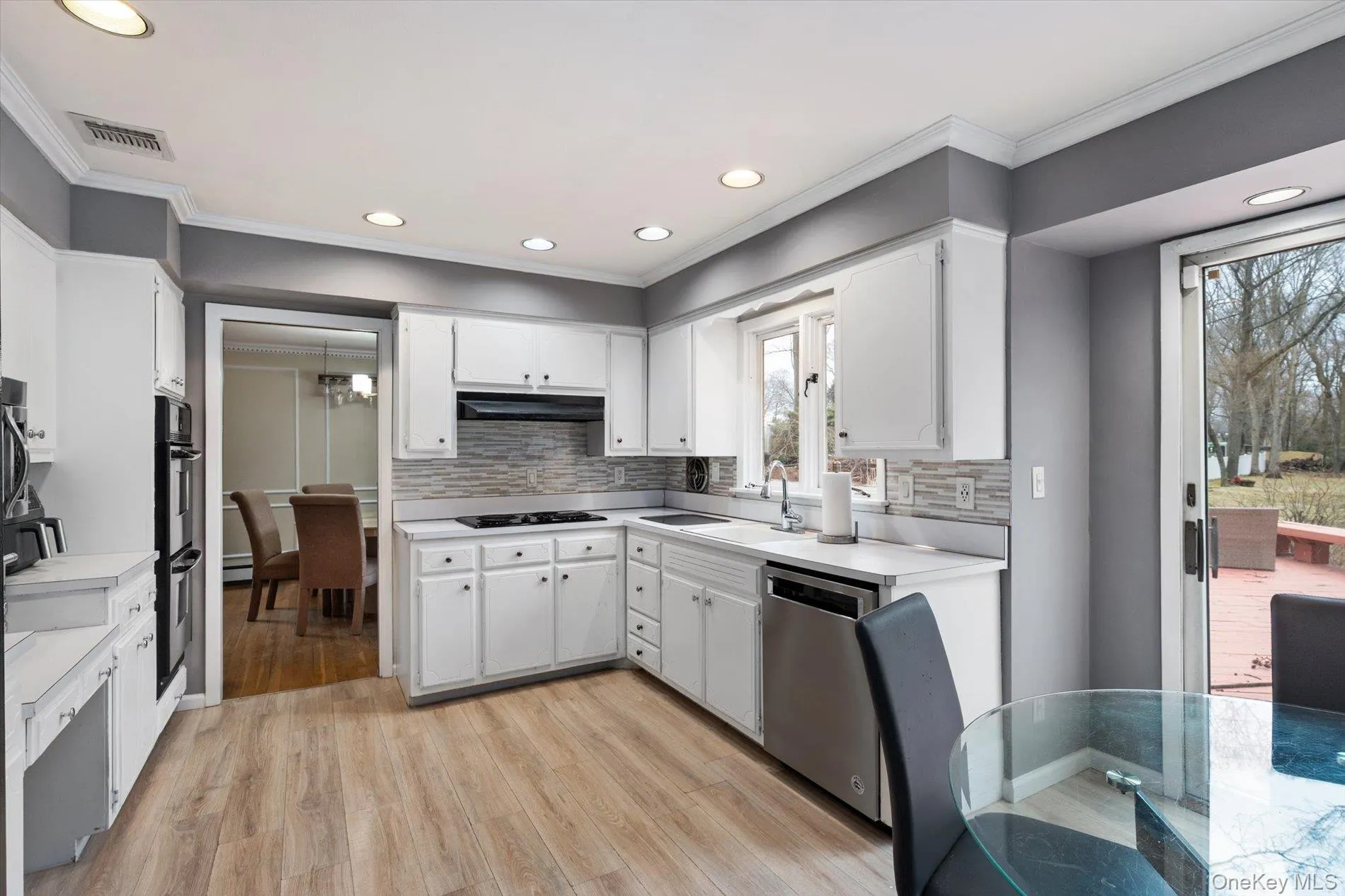 Kitchen featuring light countertops, white cabinetry, crown molding, light wood-style floors, and recessed lighting Kitchen featuring light countertops, white cabinetry, crown molding, light wood-style floors, and recessed lighting