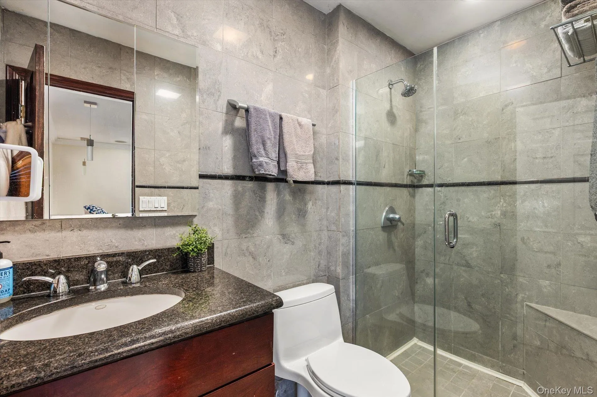 Bathroom featuring tile walls, vanity, and a shower stall Bathroom featuring tile walls, vanity, and a shower stall