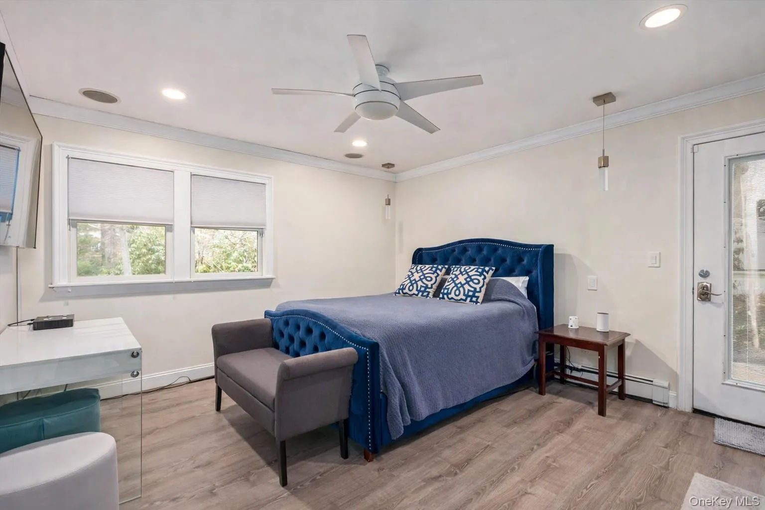 Bedroom with a baseboard heating unit, light wood-type flooring, ceiling fan, recessed lighting, and crown molding Bedroom with a baseboard heating unit, light wood-type flooring, ceiling fan, recessed lighting, and crown molding