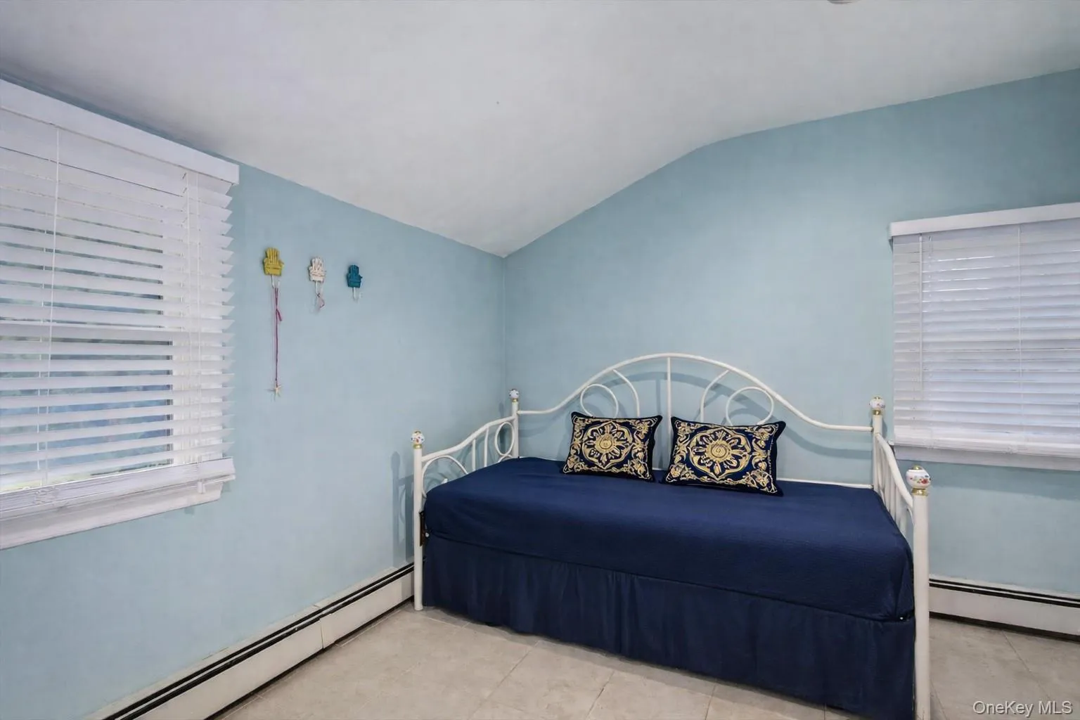 Bedroom with a baseboard radiator, lofted ceiling, and light tile patterned floors Bedroom with a baseboard radiator, lofted ceiling, and light tile patterned floors