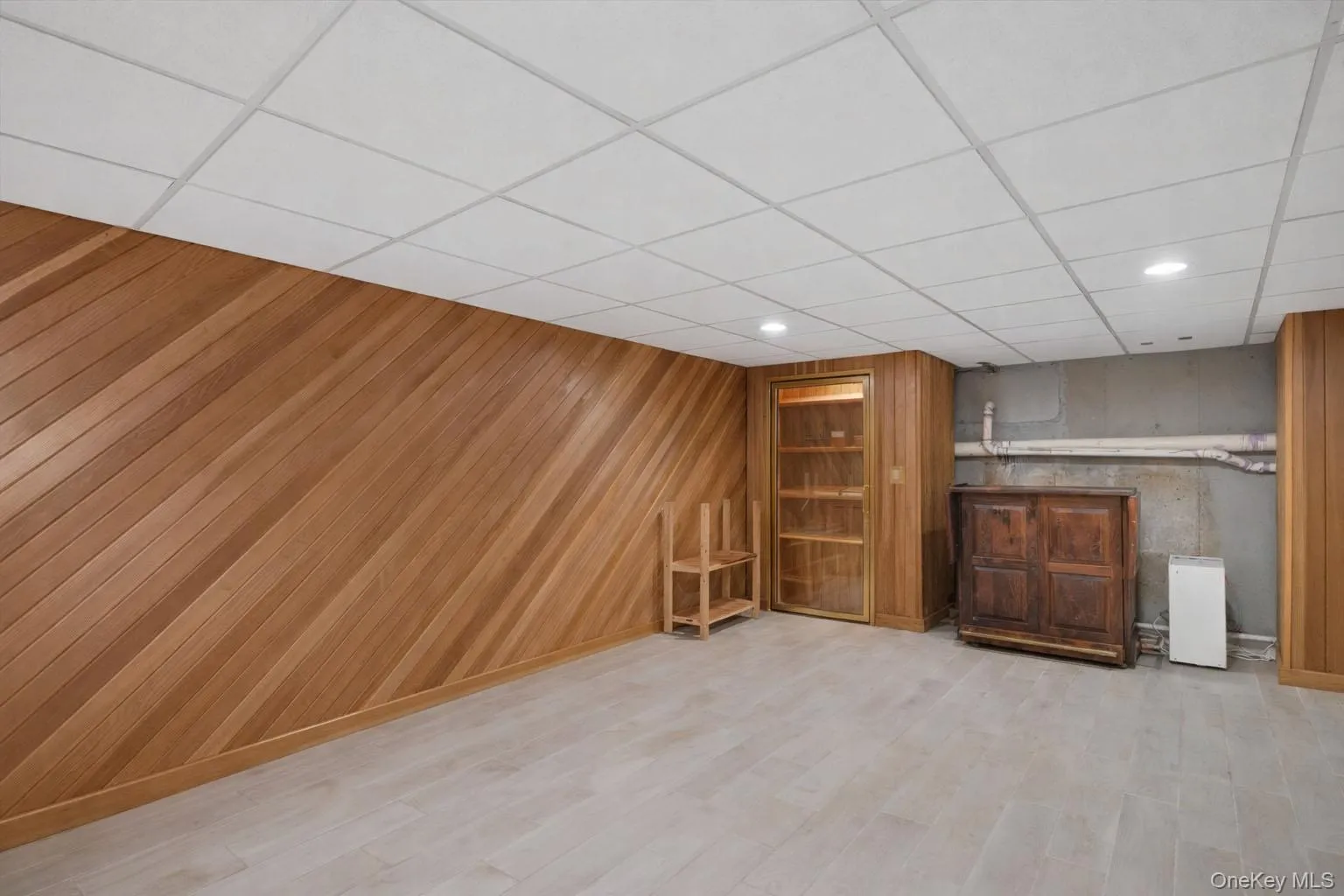 Finished below grade area with recessed lighting, a paneled ceiling, light wood finished floors, and wood walls Finished below grade area with recessed lighting, a paneled ceiling, light wood finished floors, and wood walls