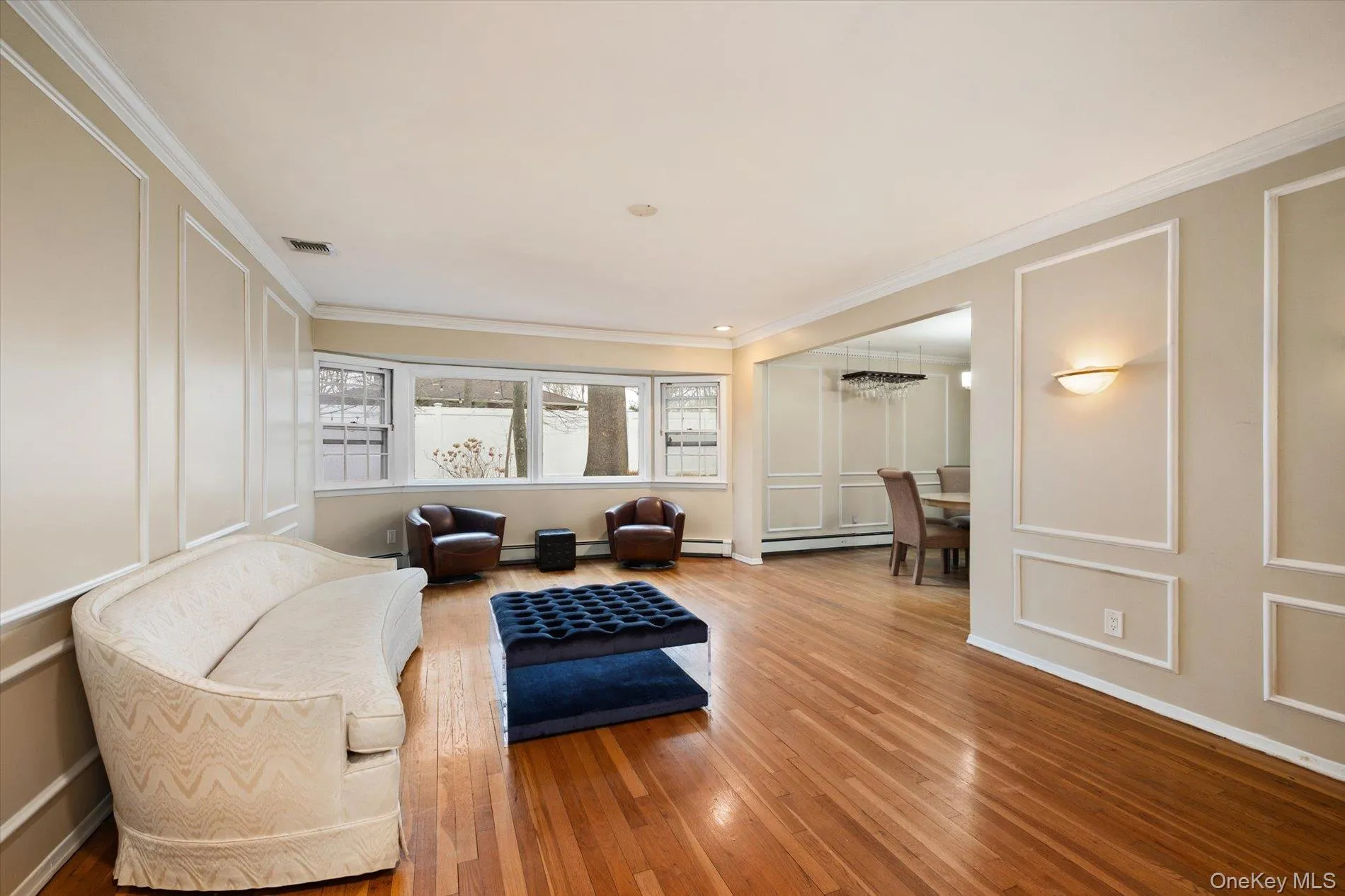 Sitting room featuring a decorative wall, hardwood / wood-style flooring, ornamental molding, and a baseboard radiator Sitting room featuring a decorative wall, hardwood / wood-style flooring, ornamental molding, and a baseboard radiator