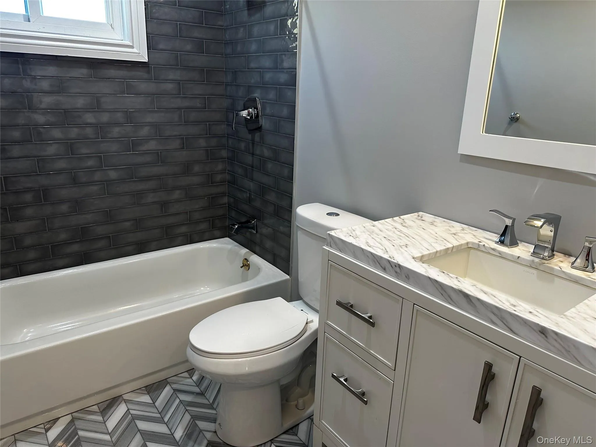 Bathroom featuring a white vanity with a marble-finish countertop, undermount sink, and chrome faucet Bathroom featuring a white vanity with a marble-finish countertop, undermount sink, and chrome faucet