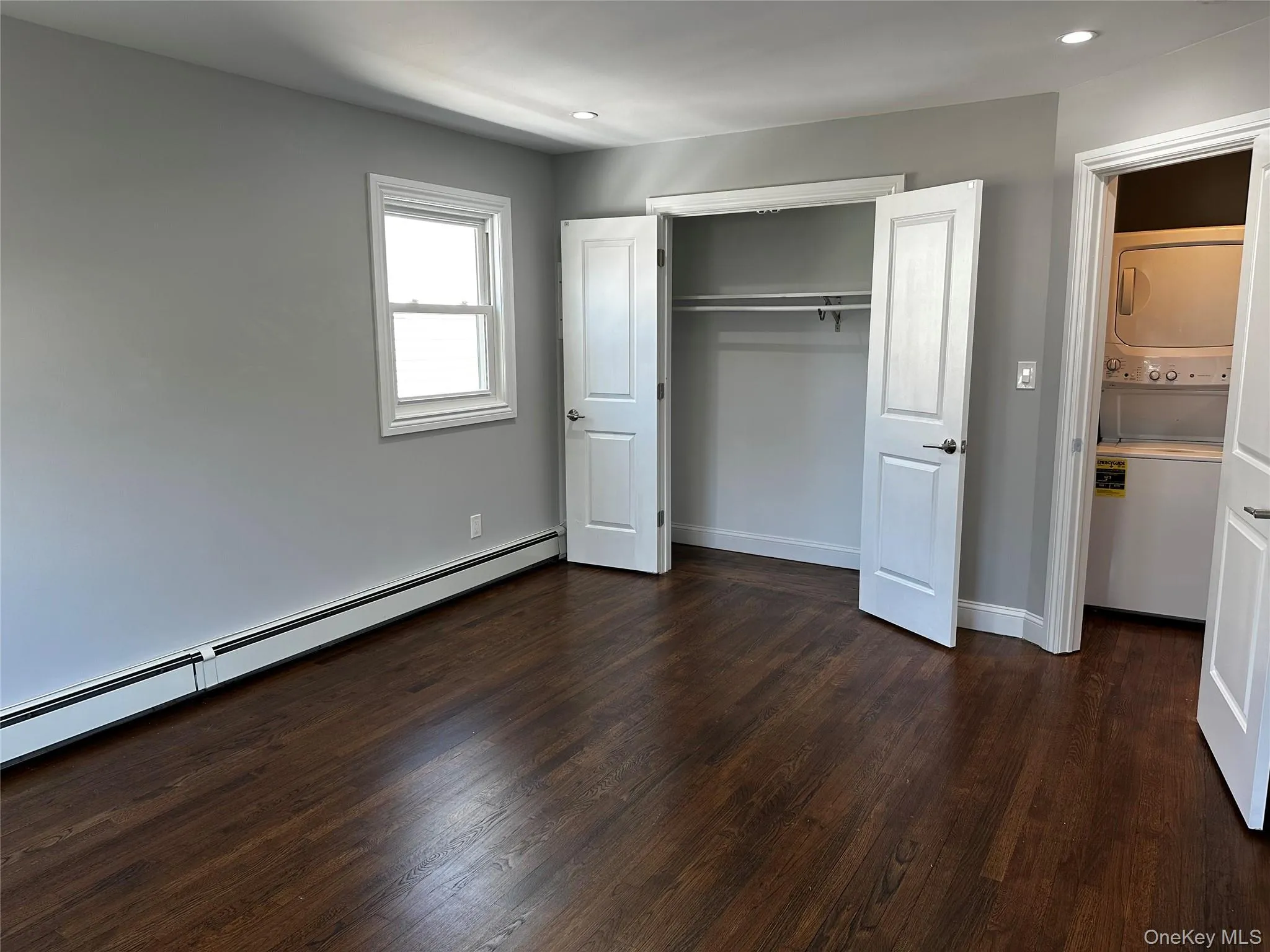 Room featuring dark wood-finish flooring, light grey painted walls, and white trim Room featuring dark wood-finish flooring, light grey painted walls, and white trim