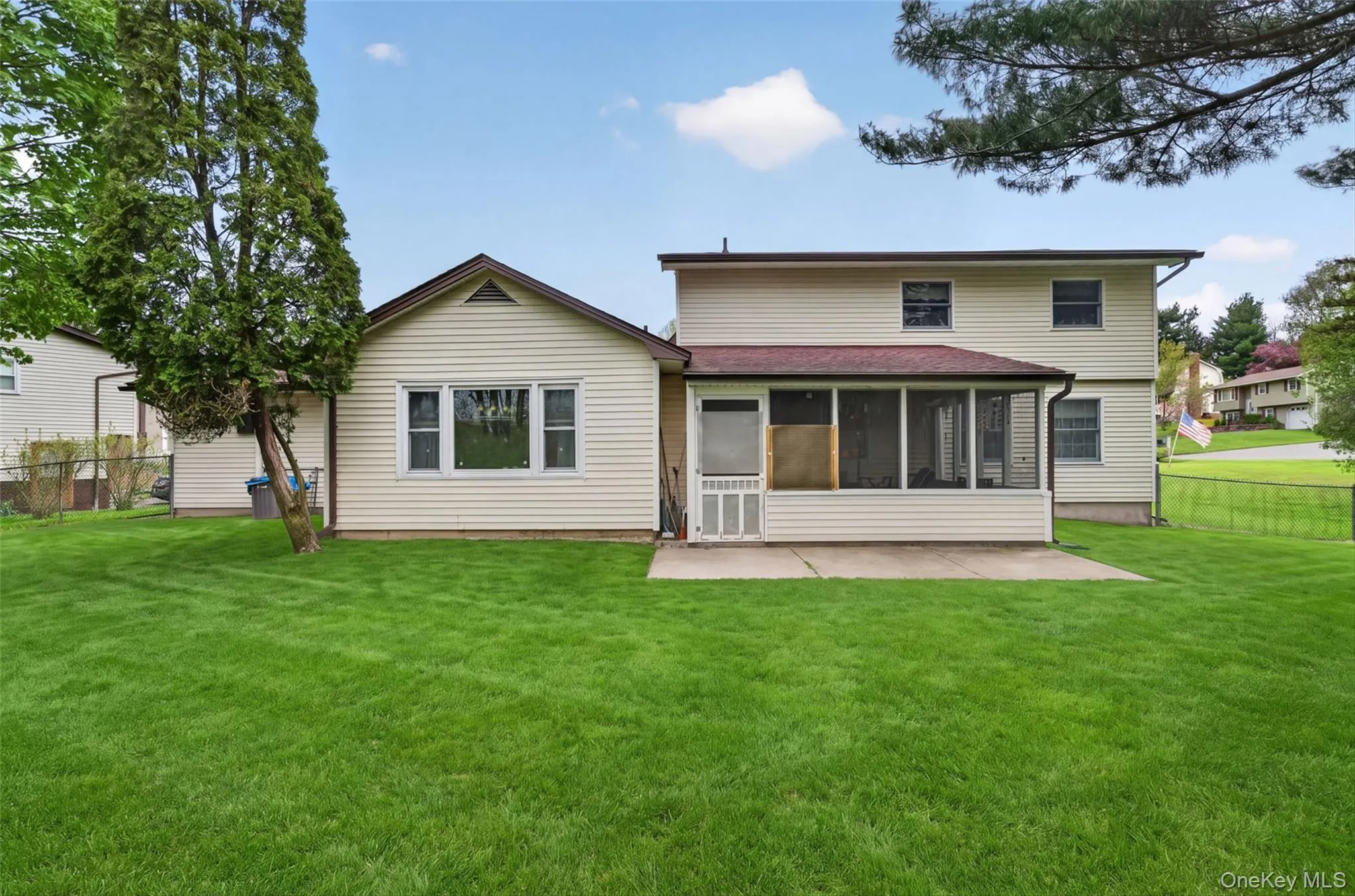 Expansive rear yard featuring a screened-in porch, concrete patio, and a two-story exterior with siding Expansive rear yard featuring a screened-in porch, concrete patio, and a two-story exterior with siding