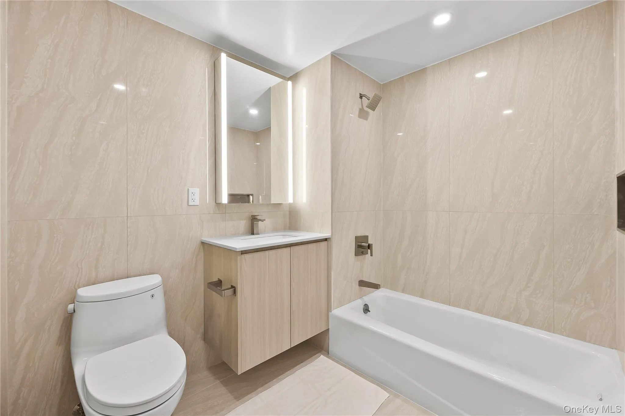 Full bath featuring vanity, tile walls, washtub / shower combination, and recessed lighting Full bath featuring vanity, tile walls, washtub / shower combination, and recessed lighting