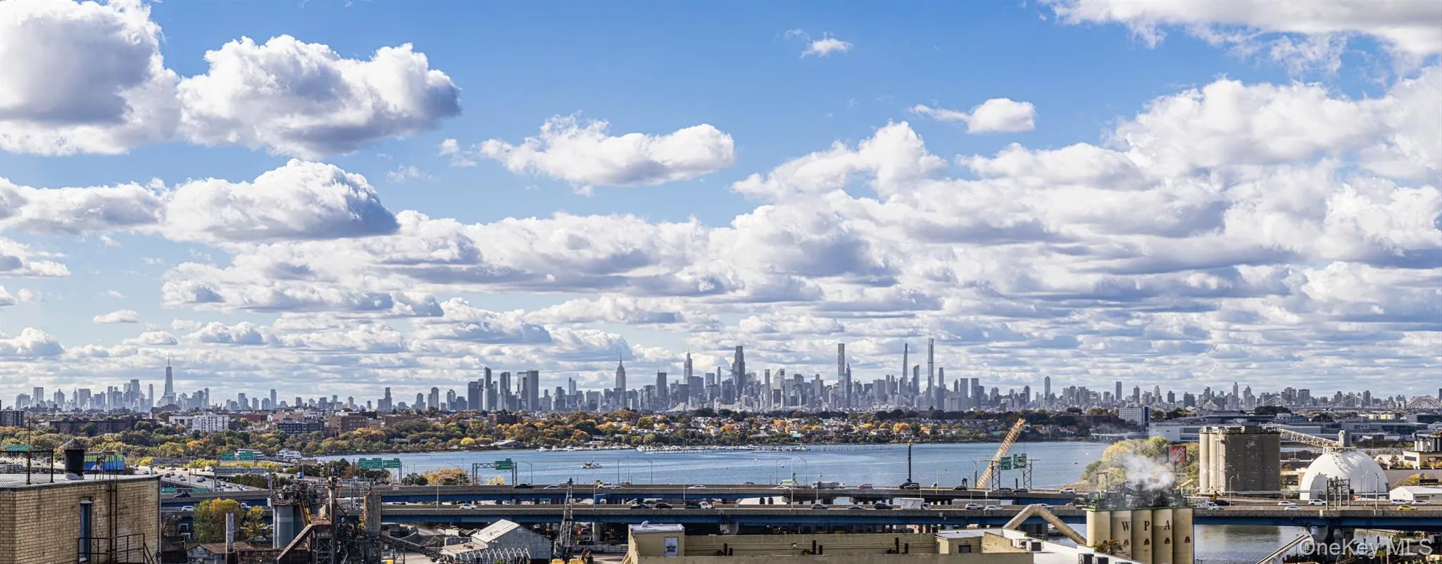 View of city skyline featuring a notable bridge and a large body of water View of city skyline featuring a notable bridge and a large body of water