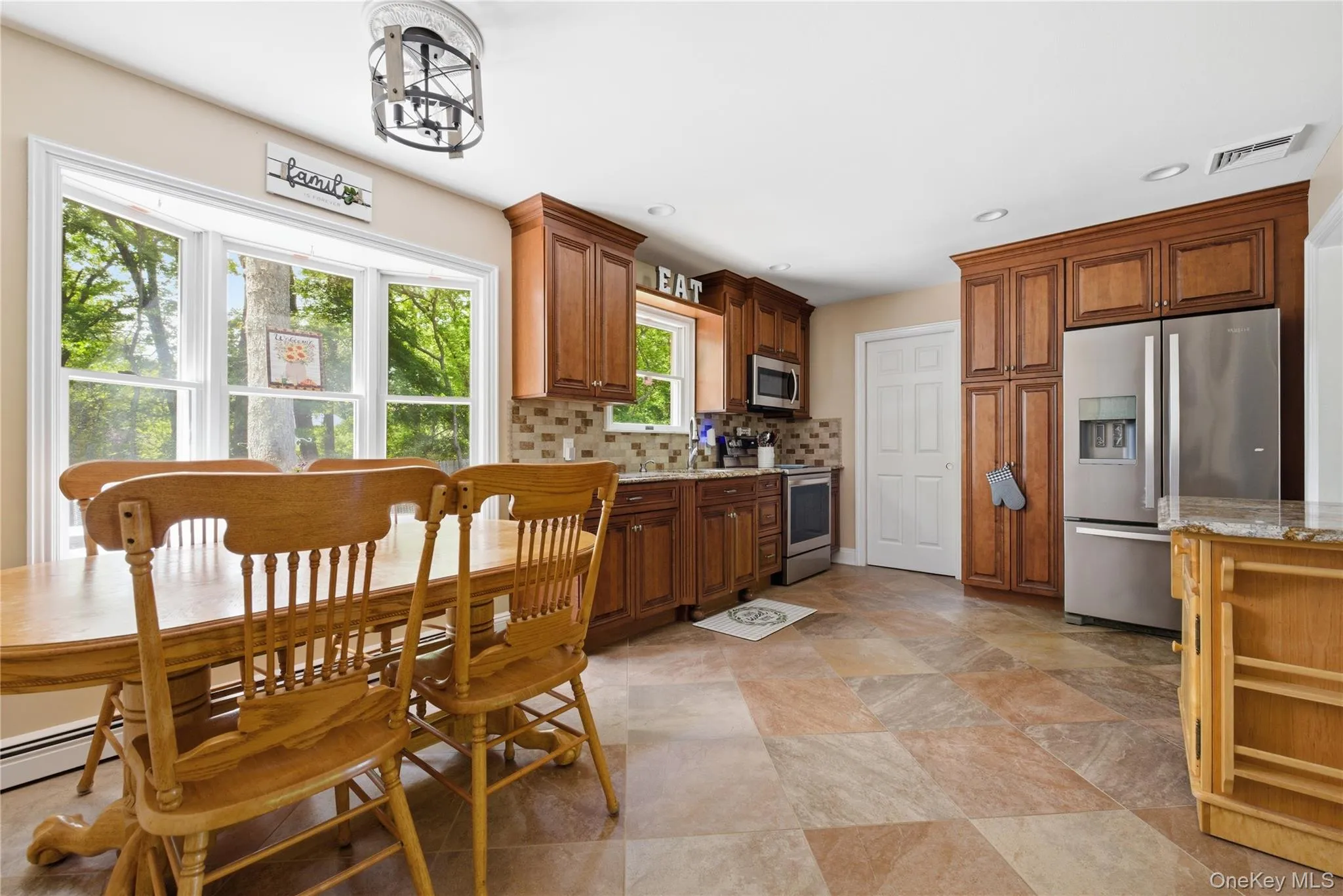 Spacious kitchen with a large bay window, rich wood cabinetry, stainless steel appliances, and multi-toned tile flooring Spacious kitchen with a large bay window, rich wood cabinetry, stainless steel appliances, and multi-toned tile flooring
