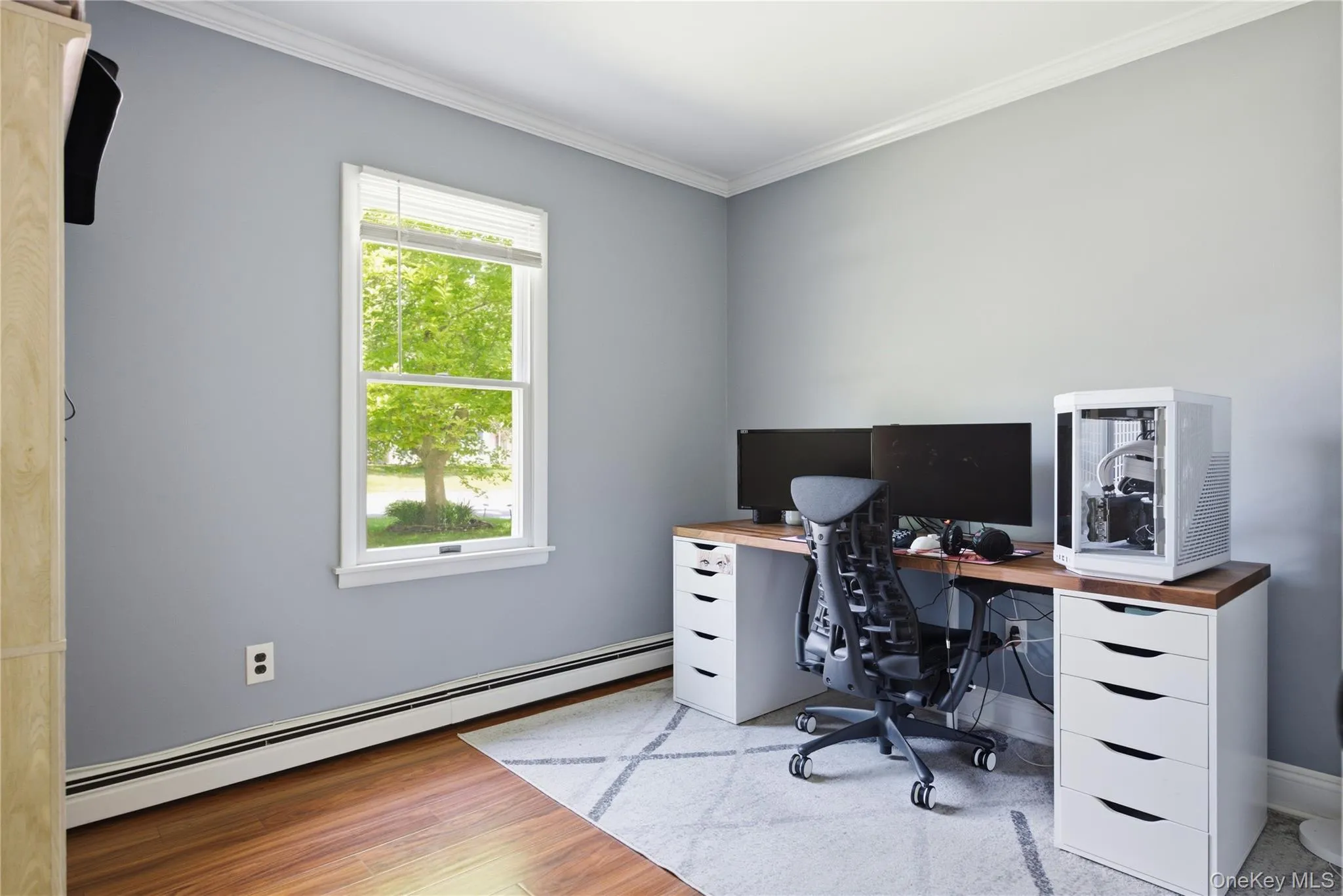 Room featuring wood-finish flooring, light gray walls, and white crown molding Room featuring wood-finish flooring, light gray walls, and white crown molding