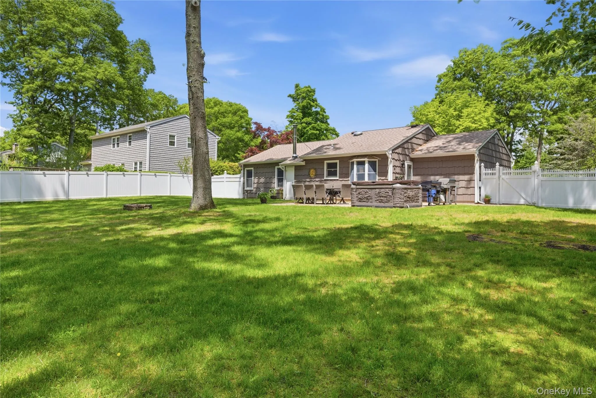 Expansive lawn area featuring a privacy fence, mature trees, and a stone patio Expansive lawn area featuring a privacy fence, mature trees, and a stone patio
