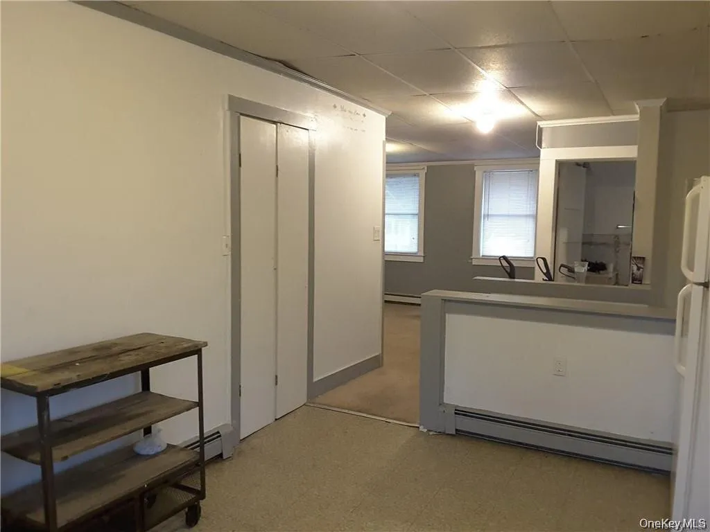Open-concept layout featuring a breakfast bar, white walls with grey trim, and multiple windows Open-concept layout featuring a breakfast bar, white walls with grey trim, and multiple windows