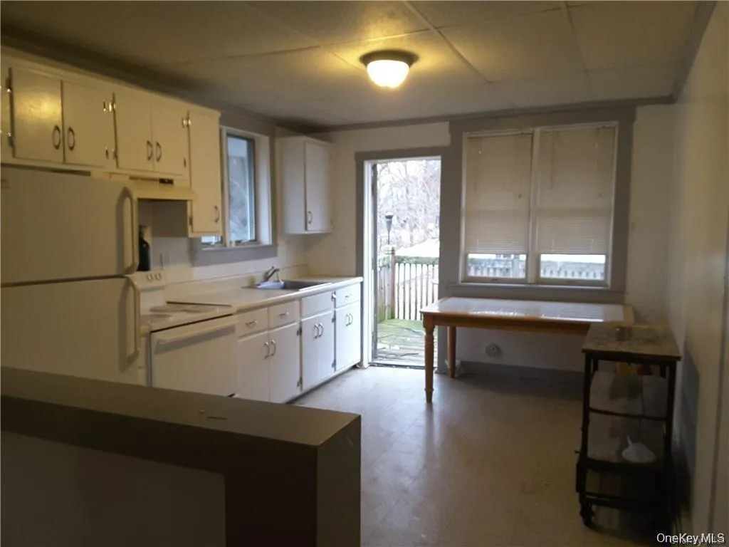 Kitchen space featuring white cabinetry, a single basin sink, and a built-in electric range Kitchen space featuring white cabinetry, a single basin sink, and a built-in electric range