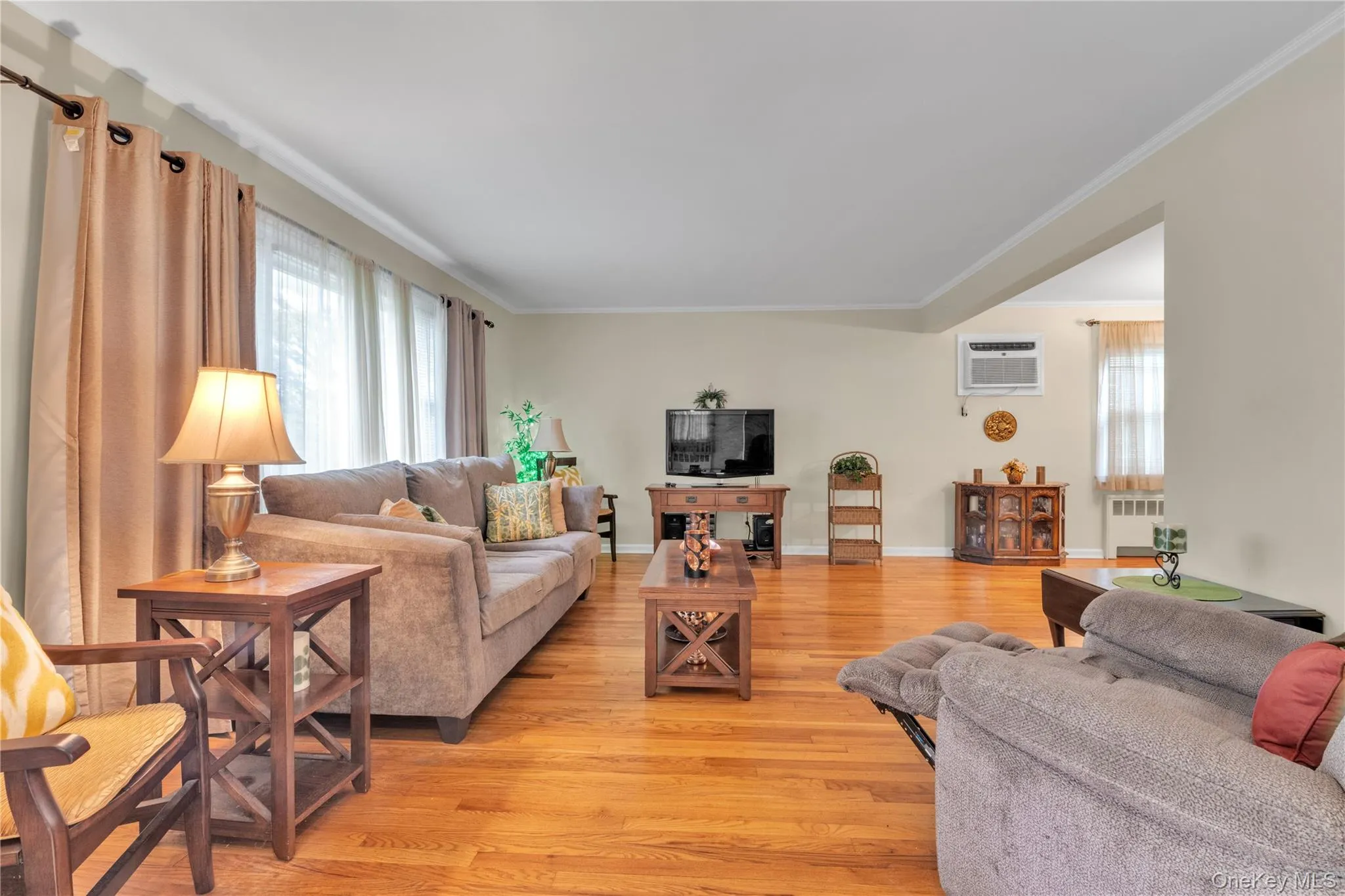 Living area featuring hardwood flooring, crown molding, and neutral wall tones Living area featuring hardwood flooring, crown molding, and neutral wall tones