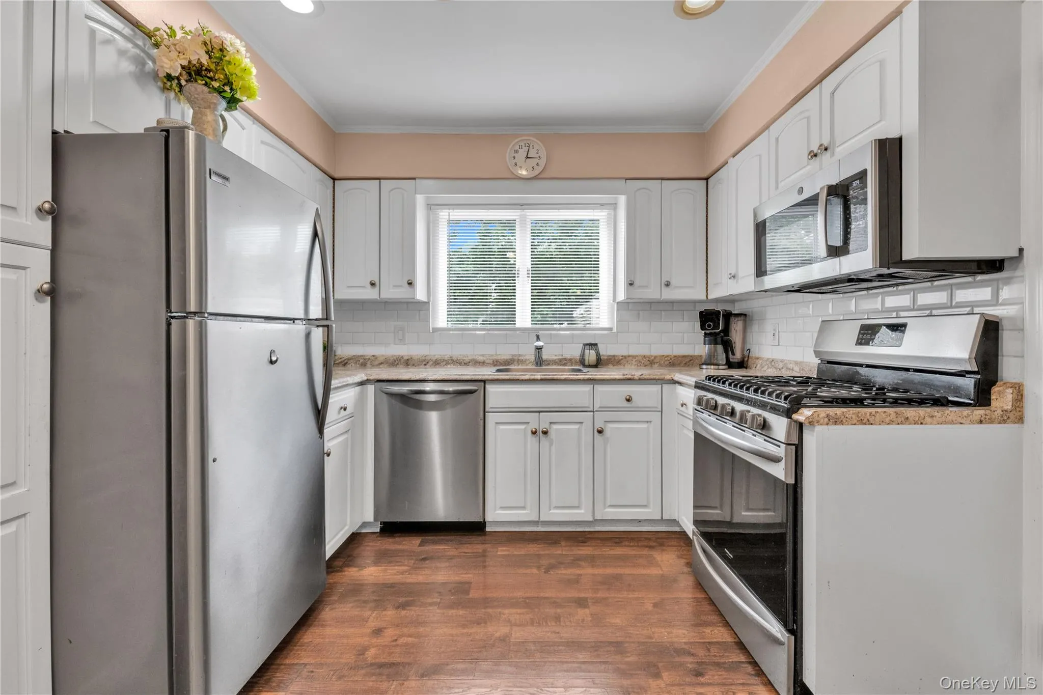 Kitchen featuring white cabinetry, stainless steel appliances, speckled countertops, a white subway tile backsplash Kitchen featuring white cabinetry, stainless steel appliances, speckled countertops, a white subway tile backsplash